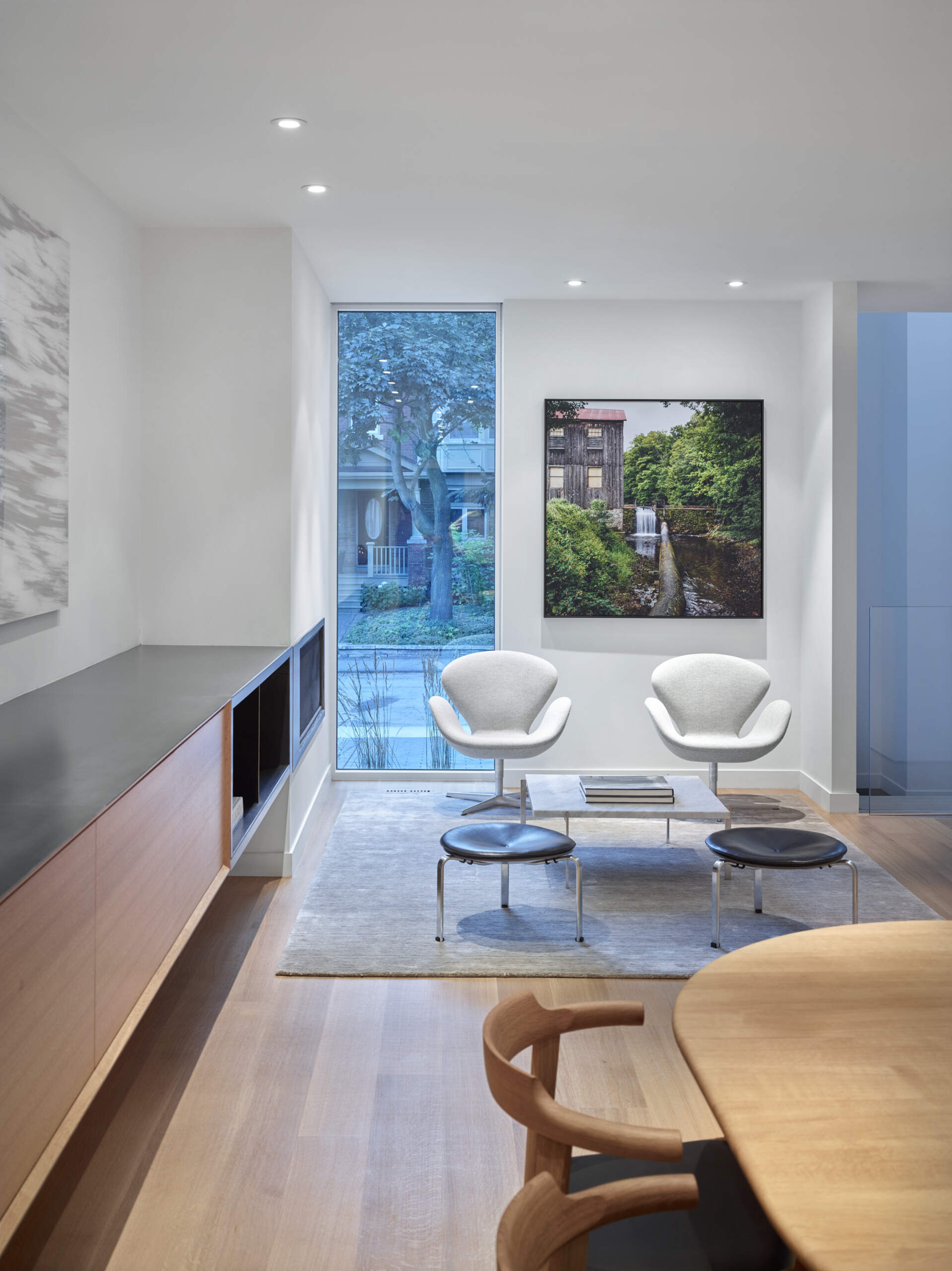 A modern sitting area with a built-in fireplace and street views inside a minimalist Toronto home designed for family living.