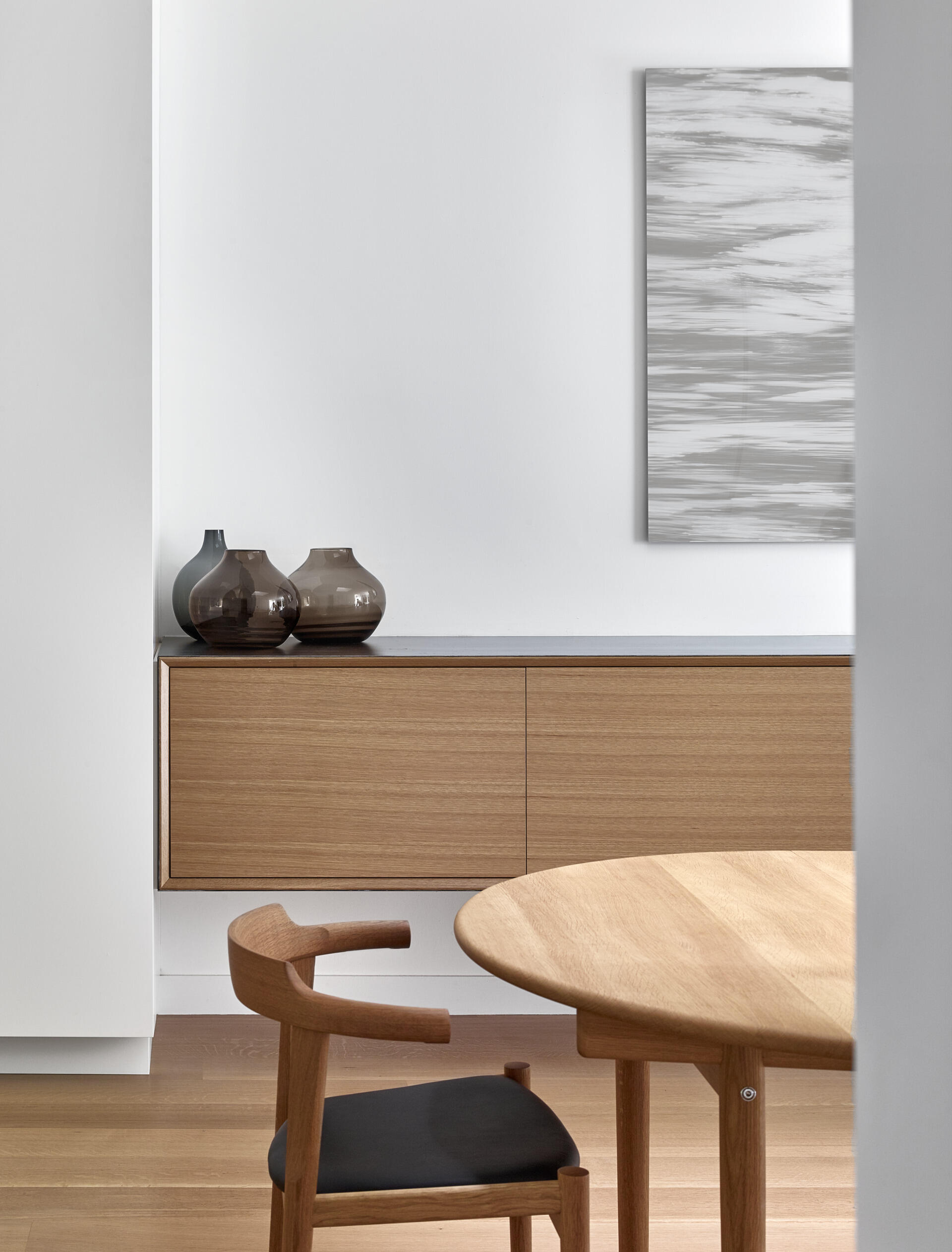 A serene dining space beneath a dramatic skylight that glows at night, blending minimal design with architectural flair.