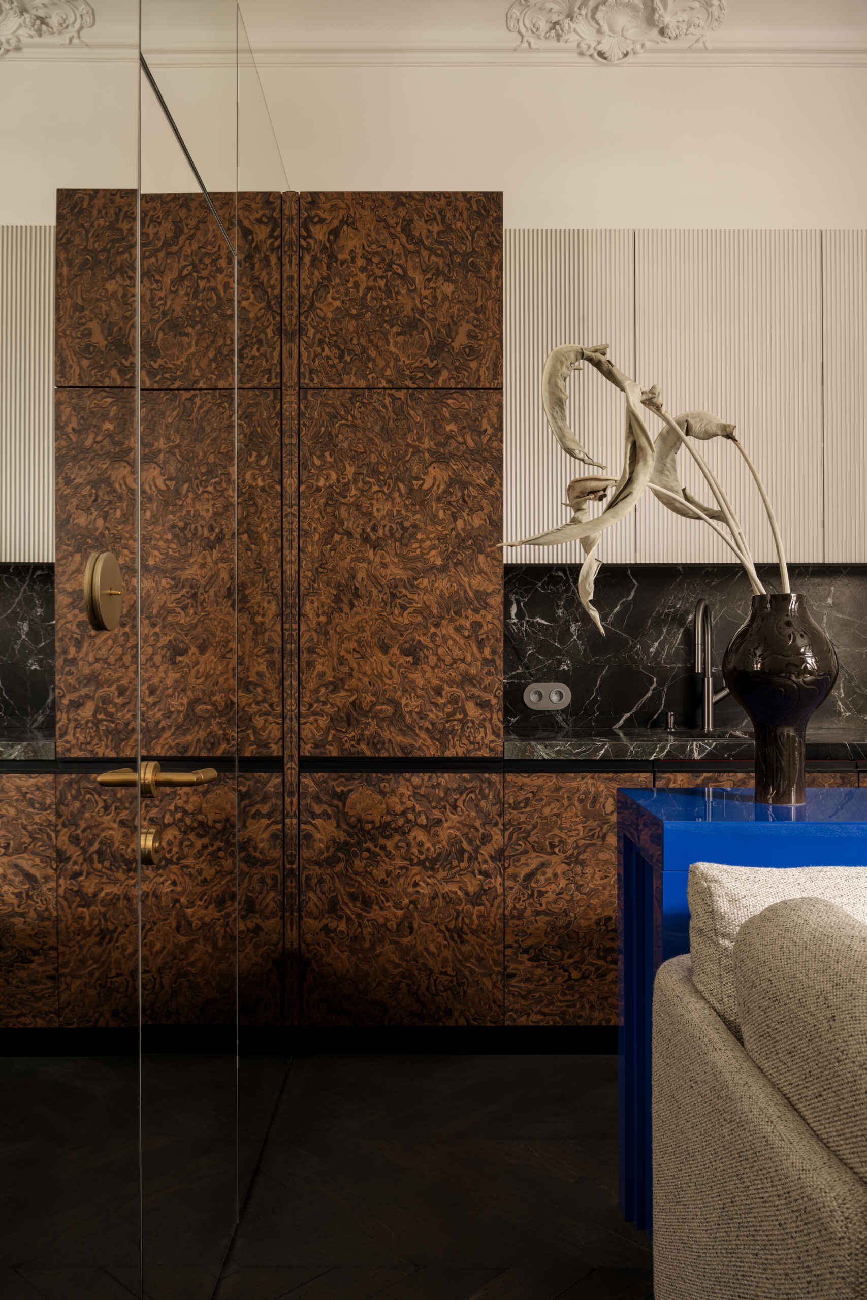 A mirrored cube hides an entire bathroom and wardrobe in plain sight. Its reflections expand the small apartment, while inside, white Calacatta Lilac marble and soft backlighting make the space feel impossibly bright and tall.