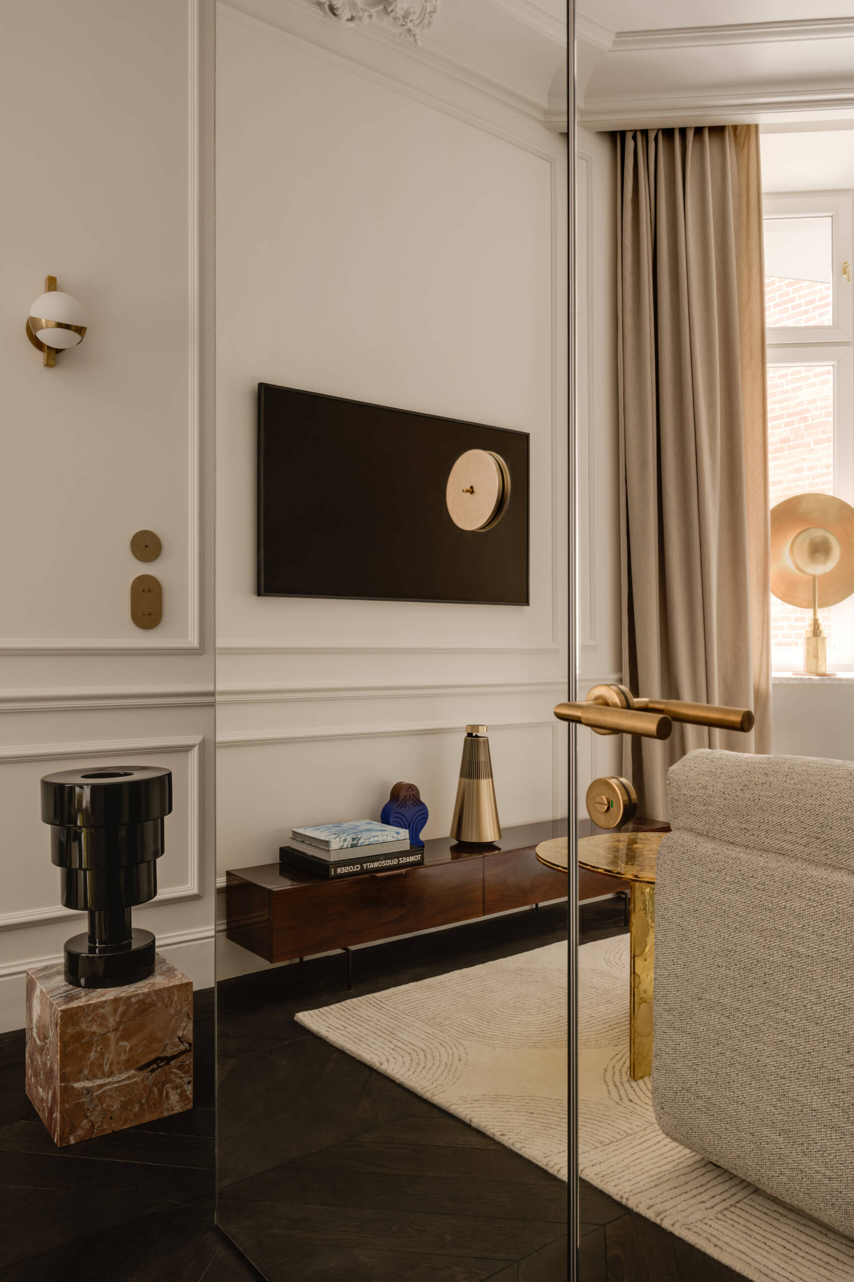 A mirrored cube hides an entire bathroom and wardrobe in plain sight. Its reflections expand the small apartment, while inside, white Calacatta Lilac marble and soft backlighting make the space feel impossibly bright and tall.