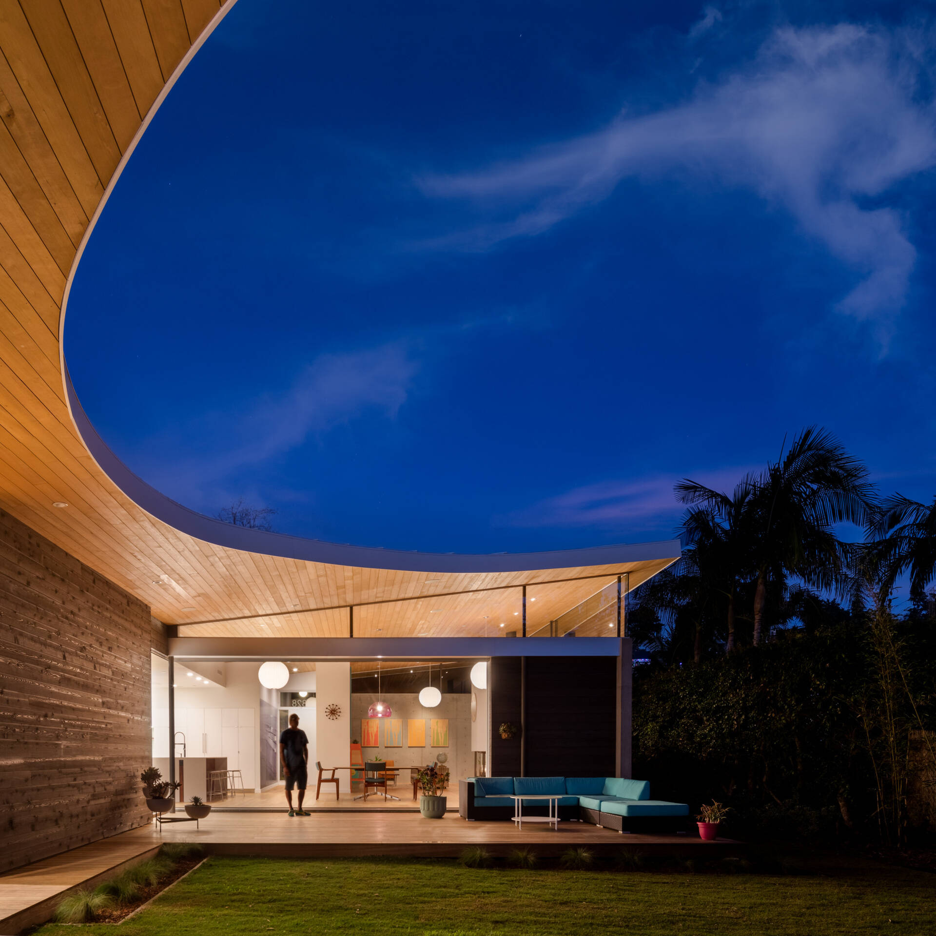 A sweeping curved roof defines the architecture of Avocado Acres House, uniting three pavilions around a central courtyard. Influenced by mid-century modern design yet built with 21st-century sustainability, the home blends bold geometry, natural light, and playful details for a striking coastal residence.
