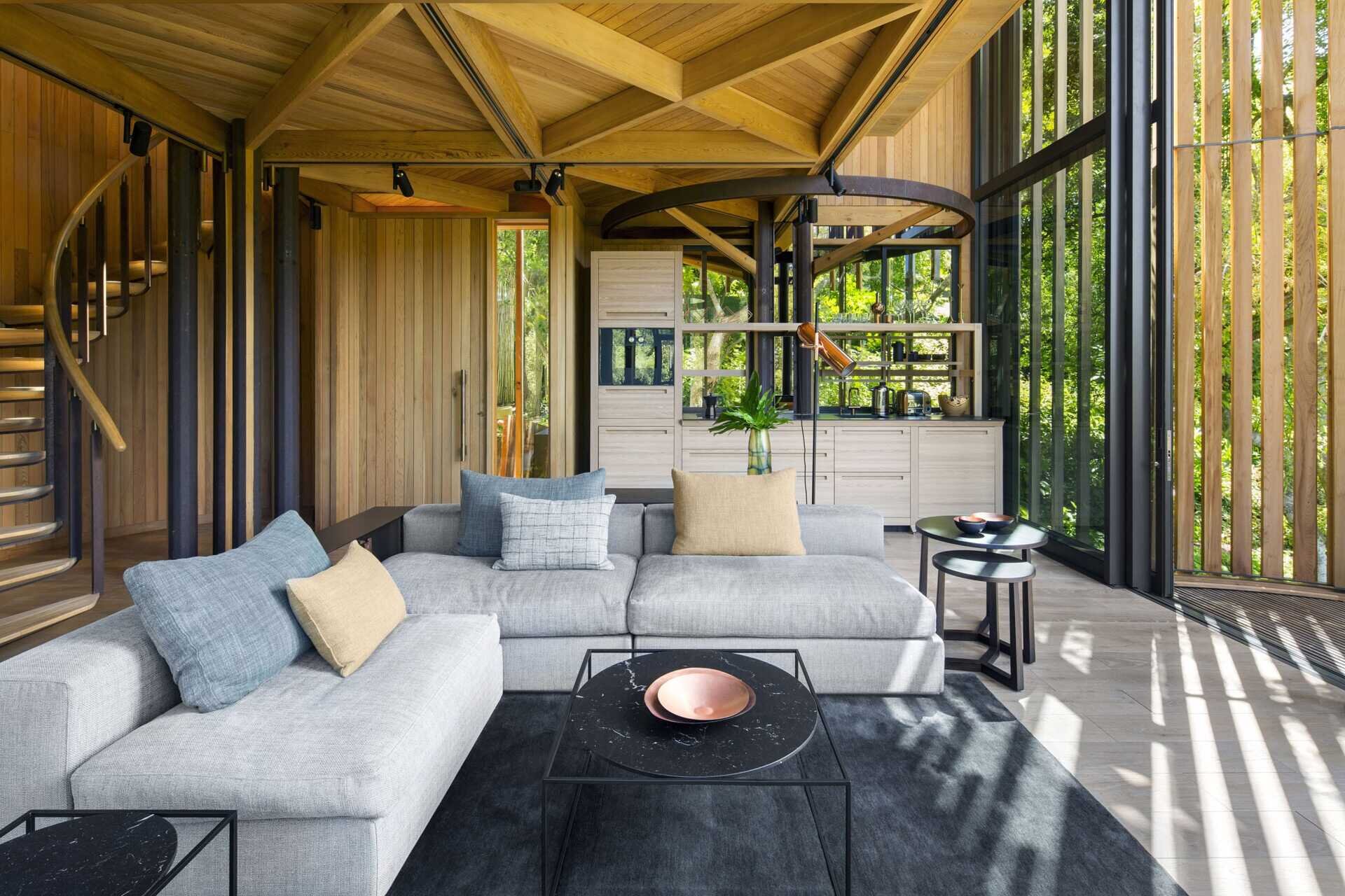 Soft greys and natural wood tones in the living room echo the surrounding forest while opening to a balcony.