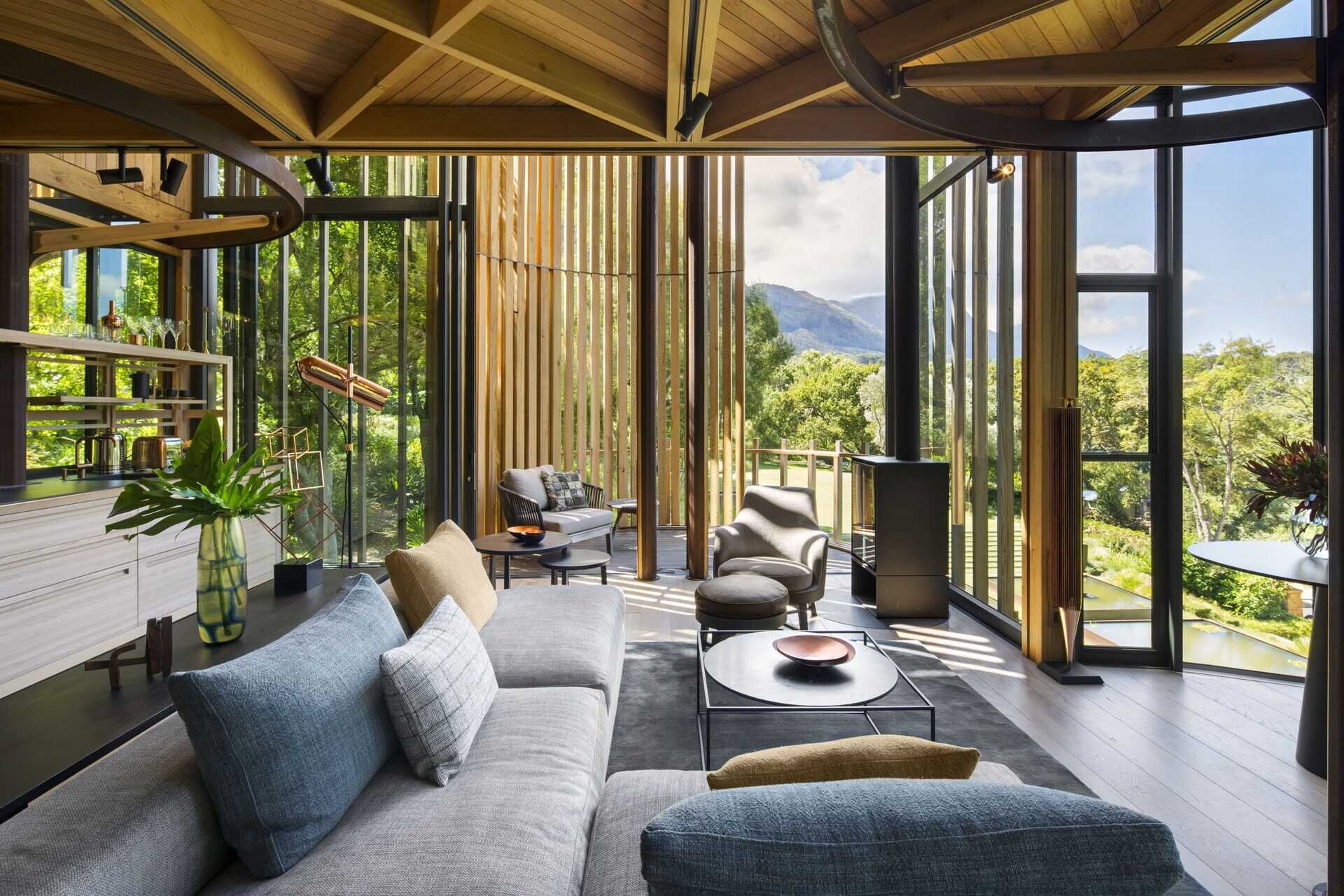 Soft greys and natural wood tones in the living room echo the surrounding forest while opening to a balcony.