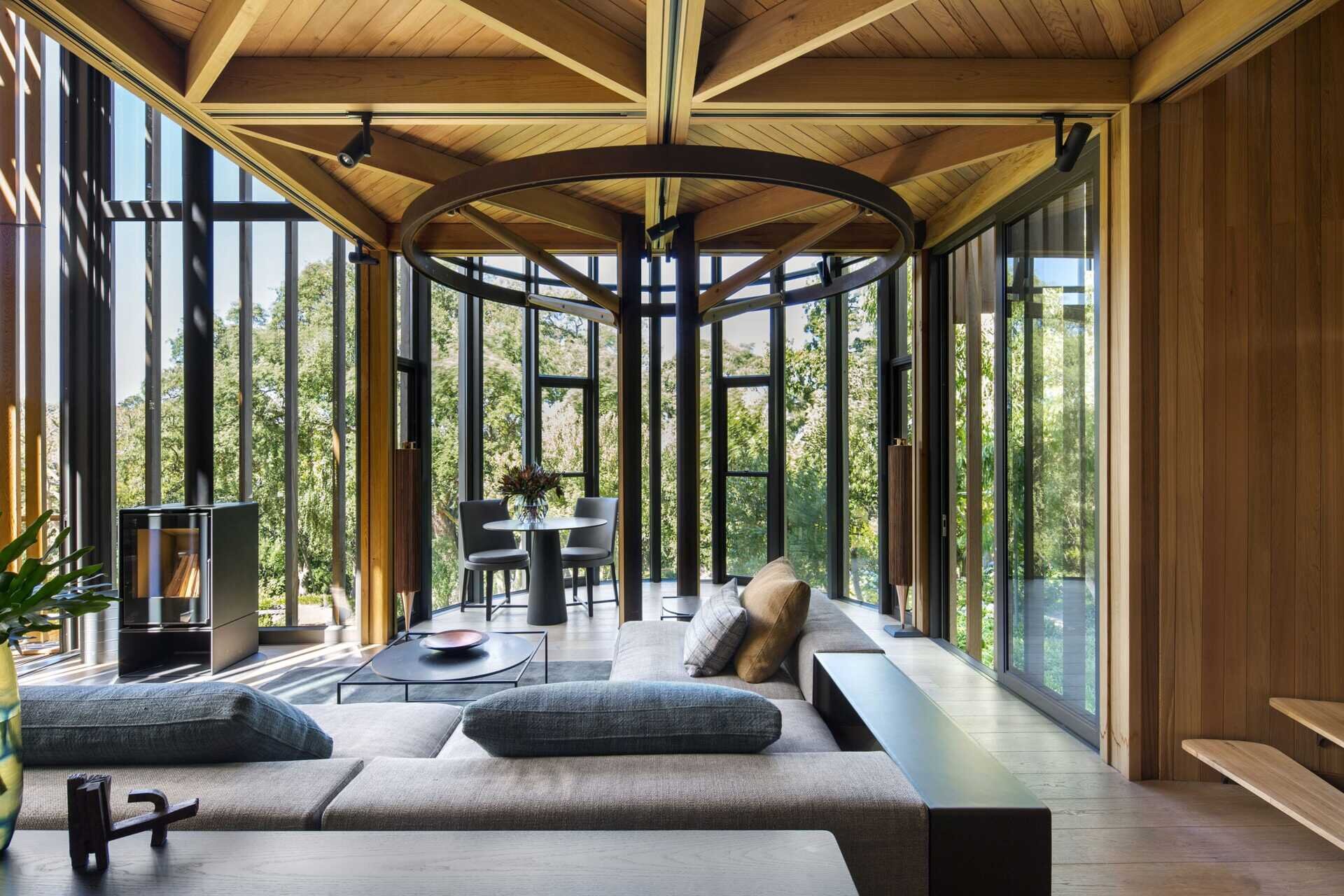 Soft greys and natural wood tones in the living room echo the surrounding forest while opening to a balcony.