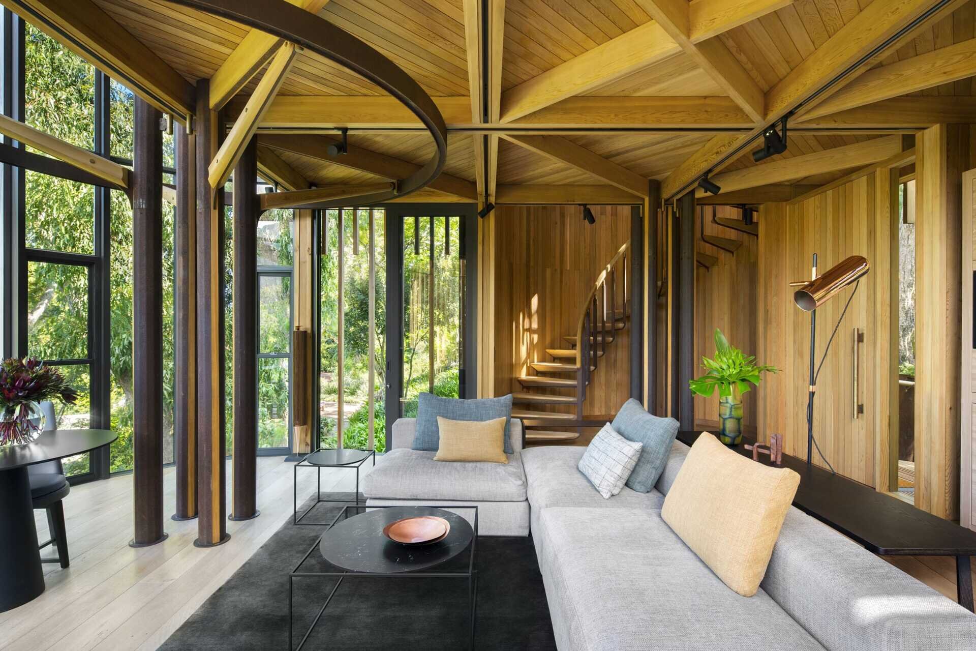 Soft greys and natural wood tones in the living room echo the surrounding forest while opening to a balcony.