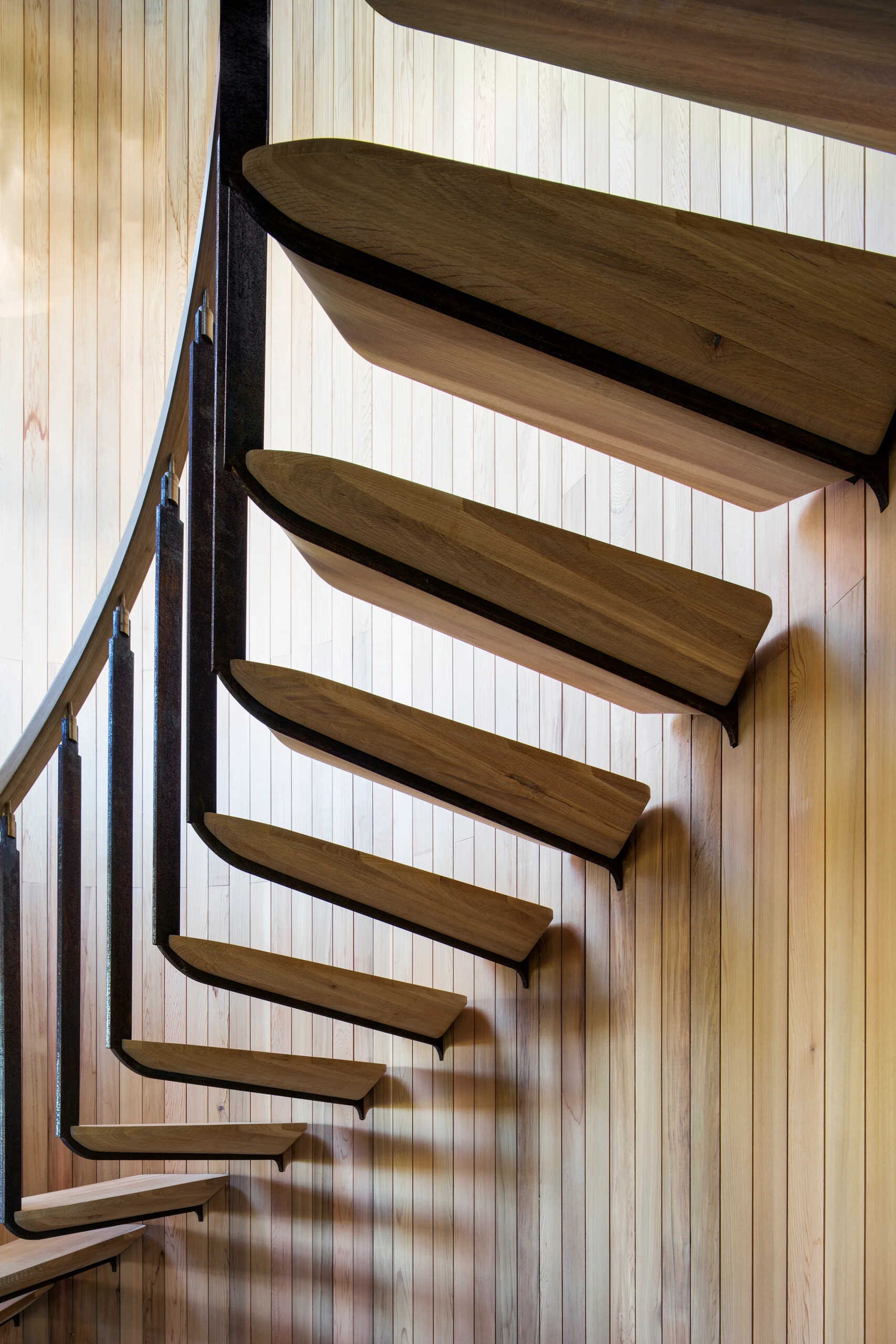 A spiral staircase of timber and steel winds through the home, connecting its canopy-level spaces.
