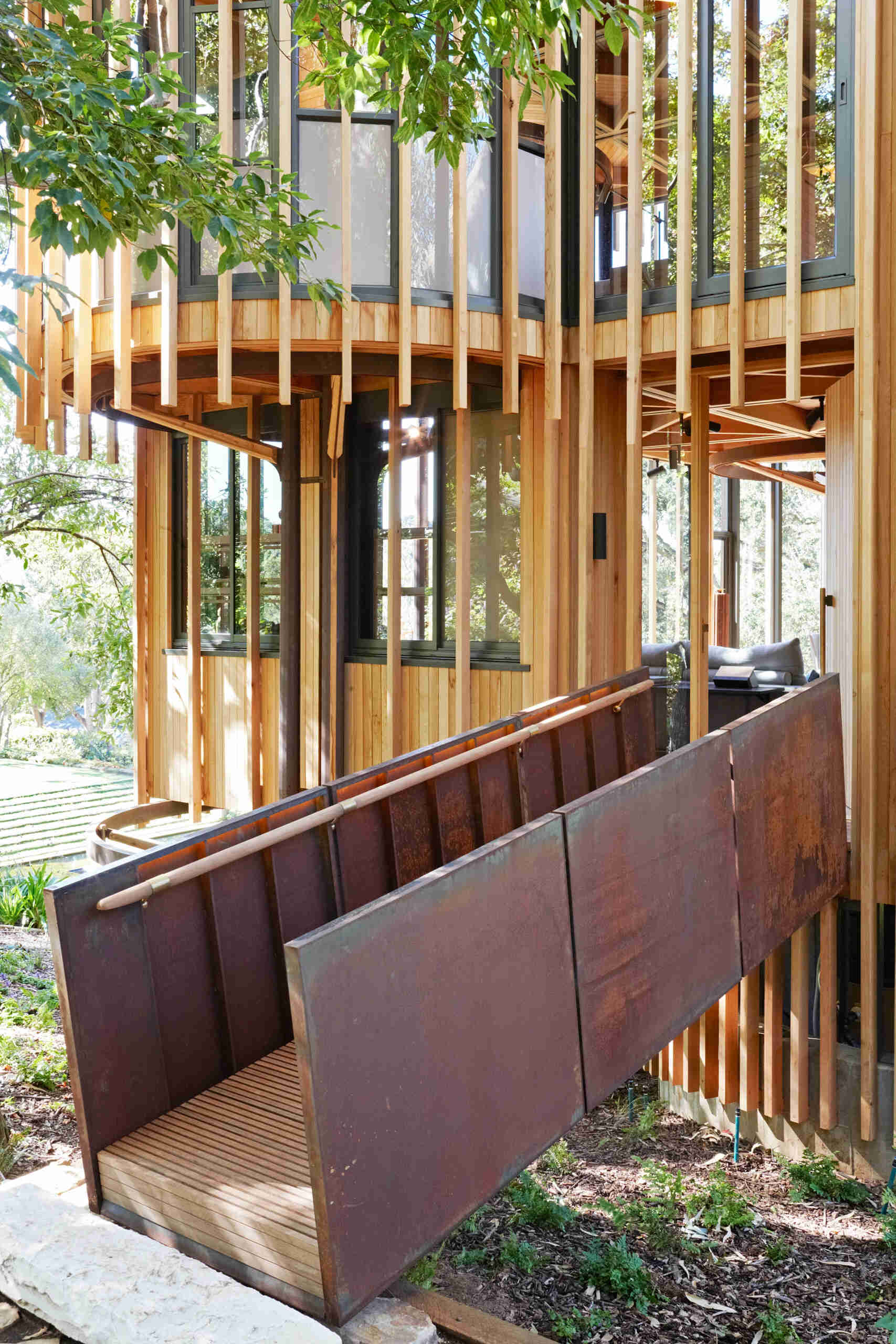 A suspended timber and steel ramp leads into the home, setting the tone for its blend of lightness and strength.