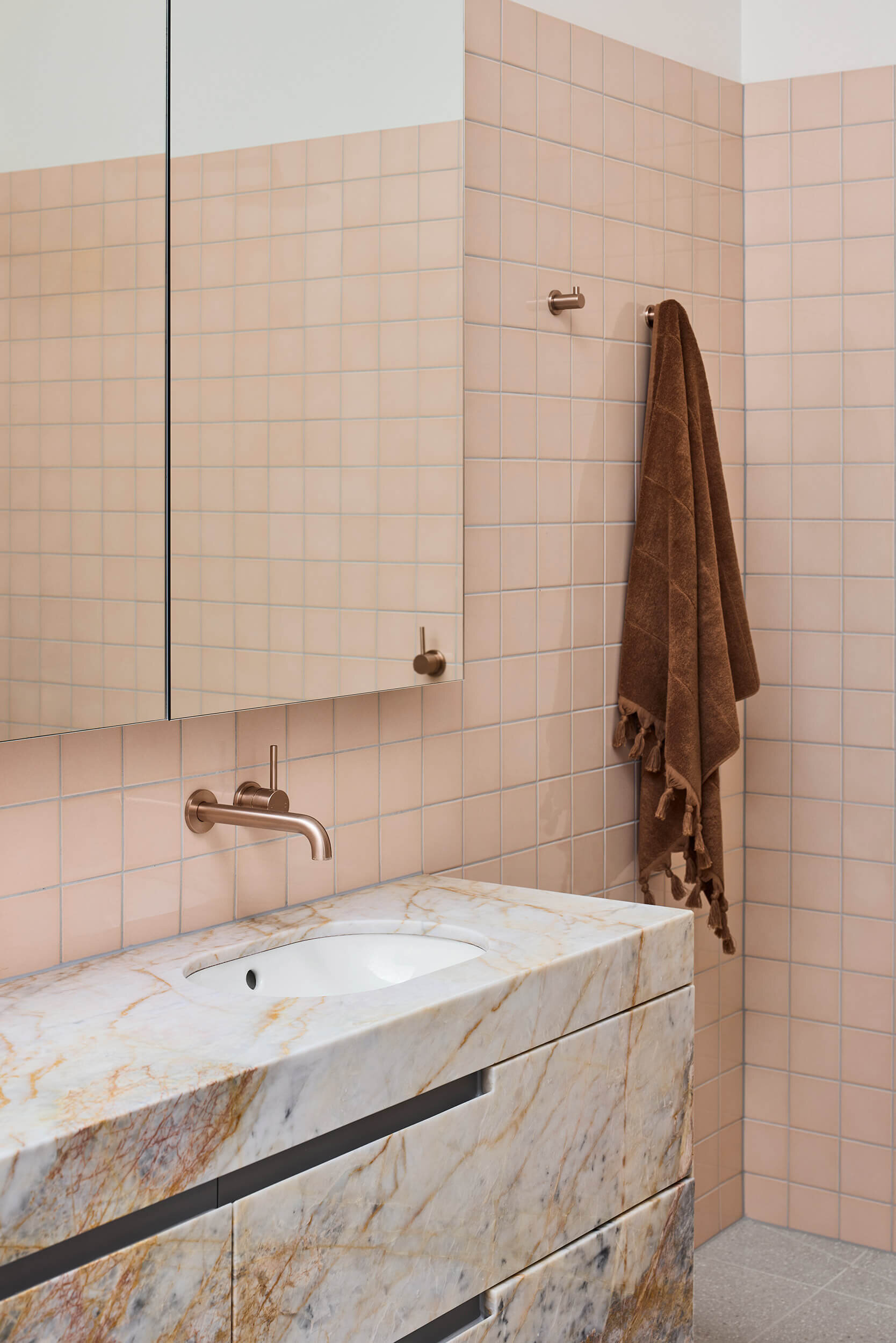 Australian marble with apricot and copper undertones carries through this ensuite bathroom, where color and texture build a sense of intimacy.