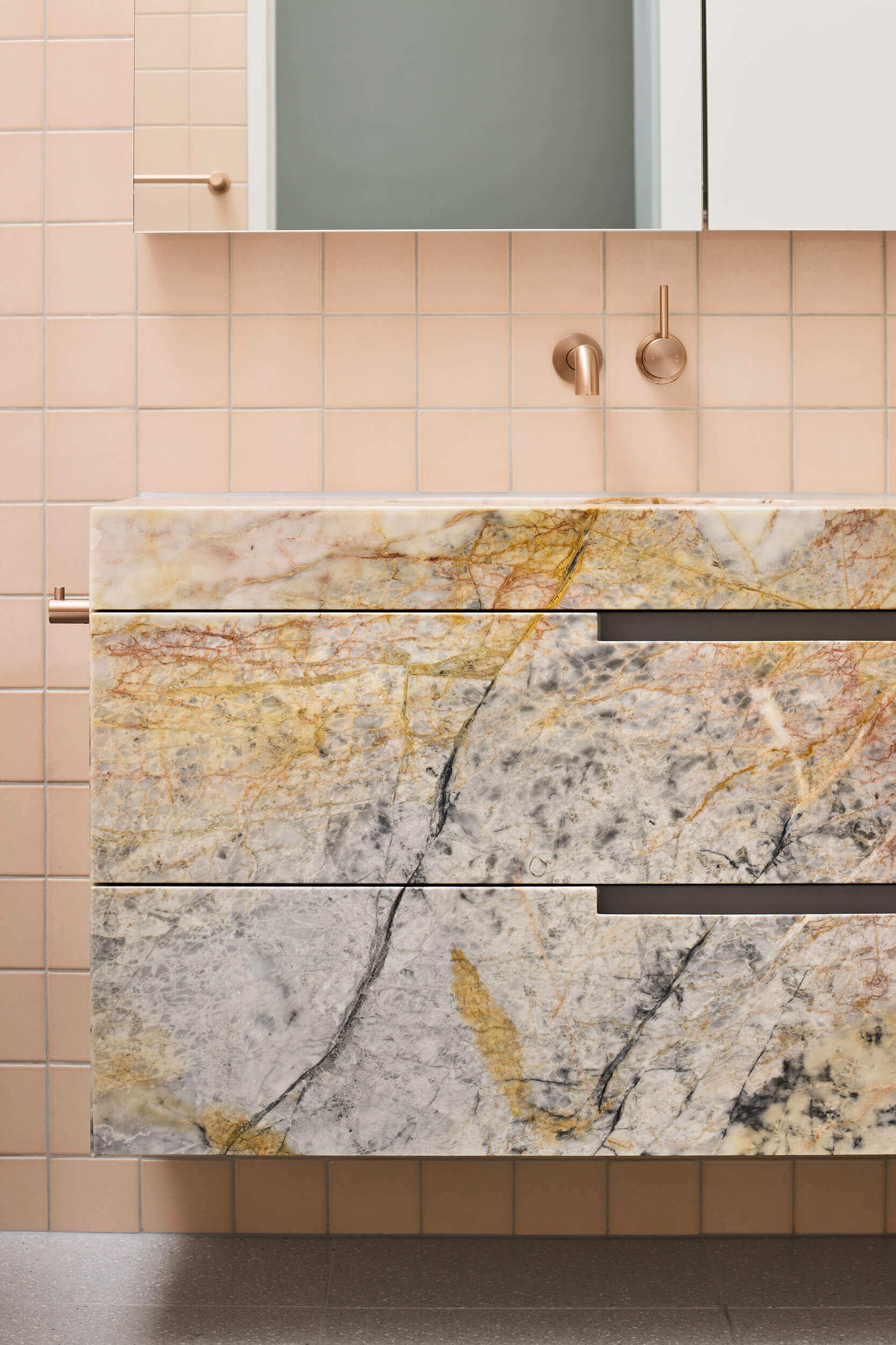 Australian marble with apricot and copper undertones carries through this ensuite bathroom, where color and texture build a sense of intimacy.