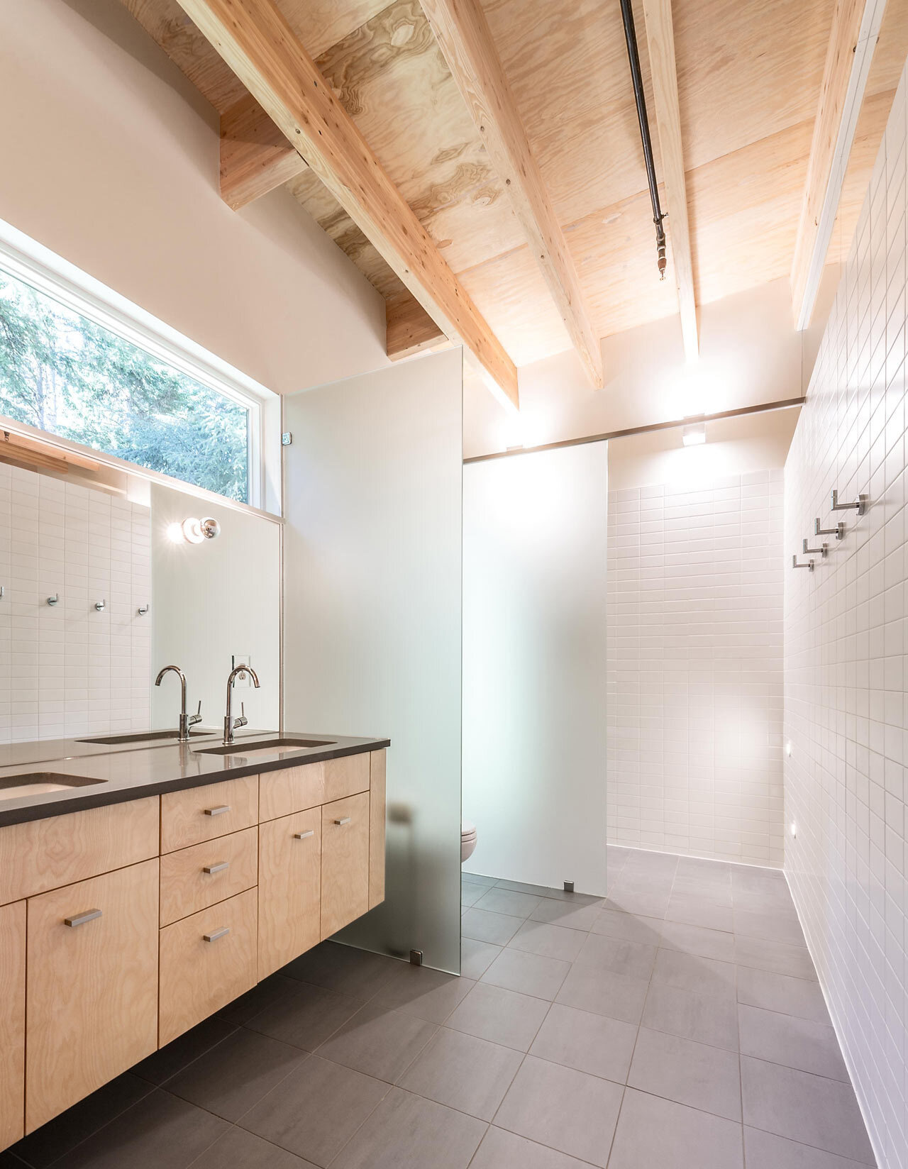 Frosted glass partitions and natural materials make this minimalist bathroom feel open, bright, and beautifully calm.