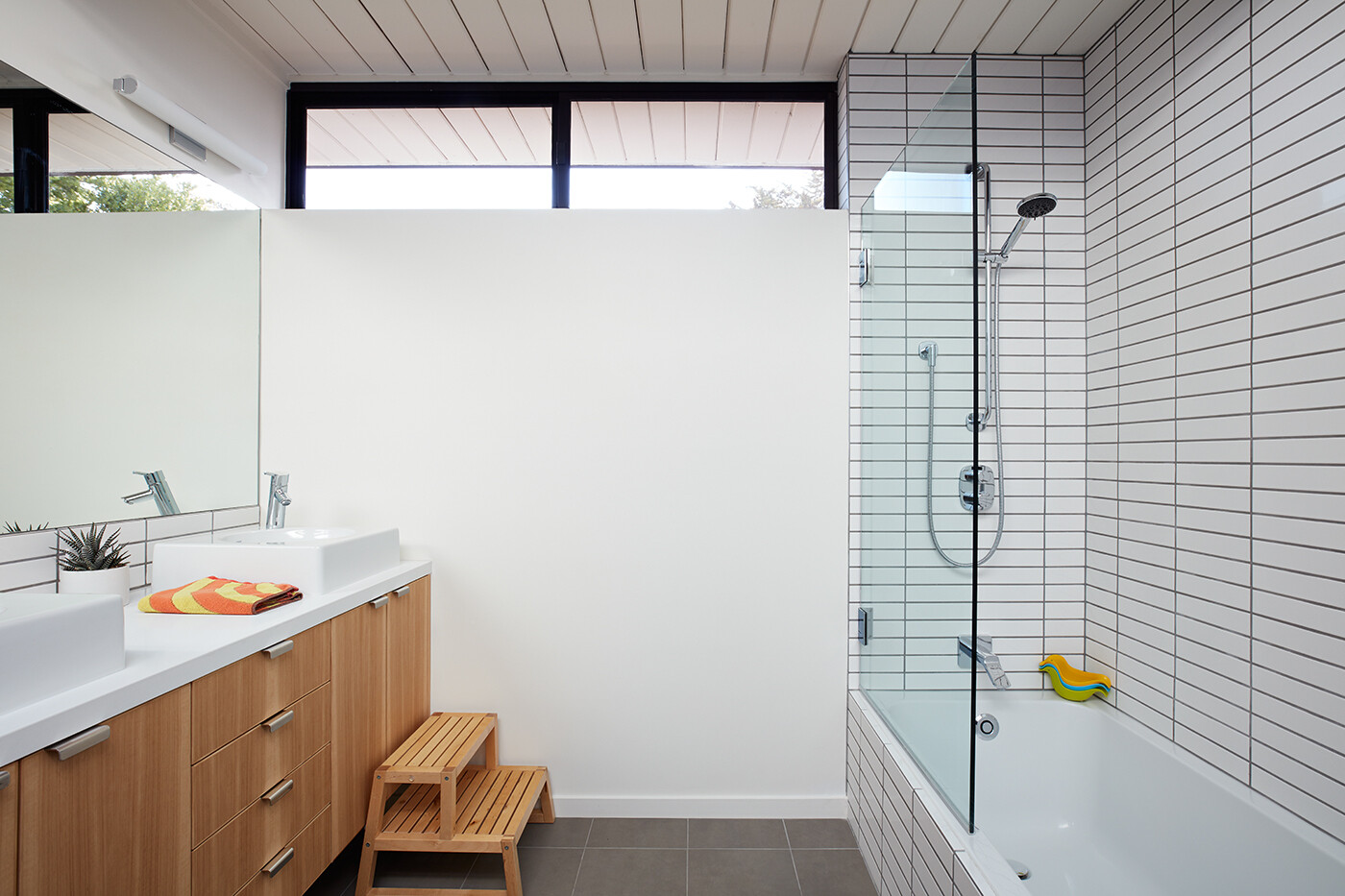 Elegant bathrooms with soft grey tones and bright finishes complete this Eichler’s understated modern look.