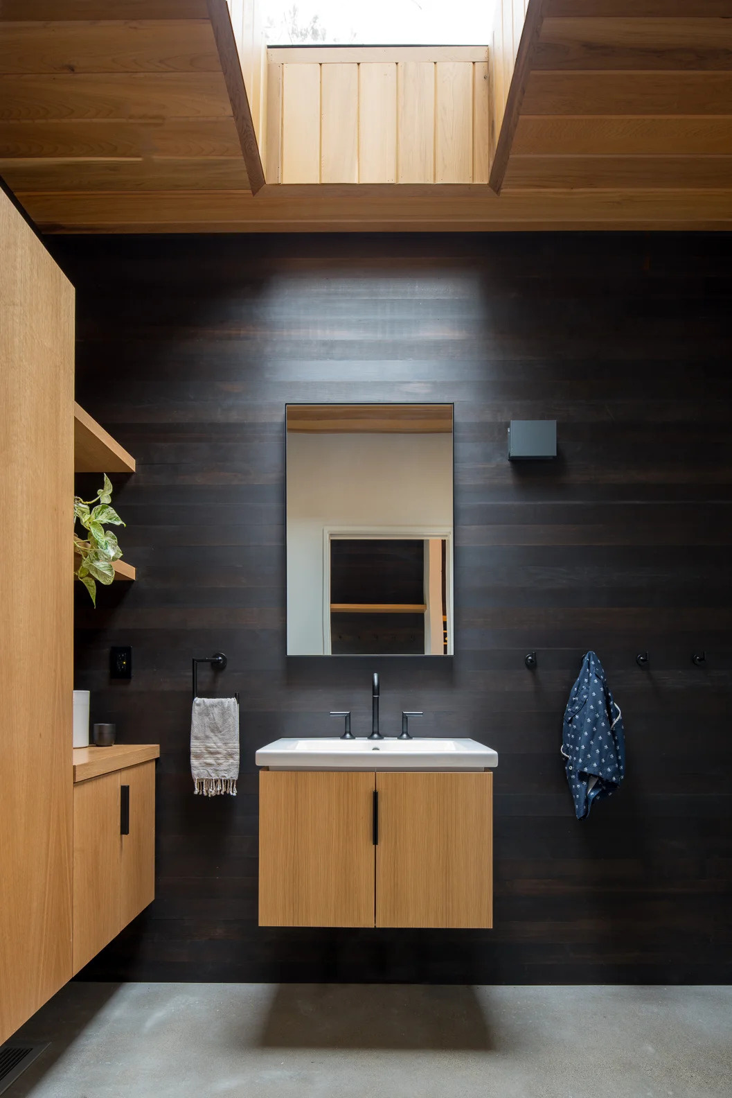 A modern bathroom with dark wood walls.