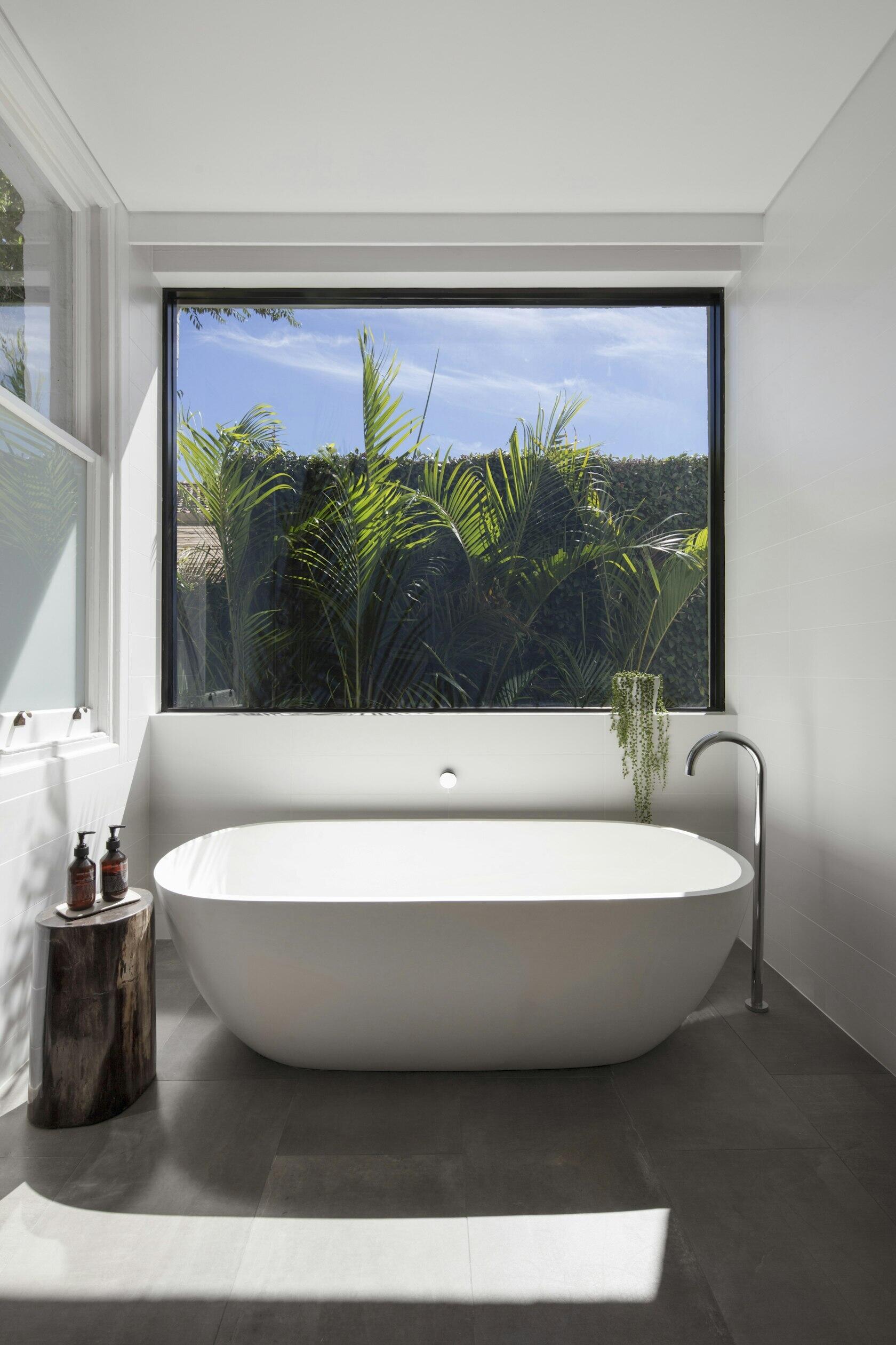 Black-framed windows and a preserved original detail tie this modern bathroom to the home’s past.