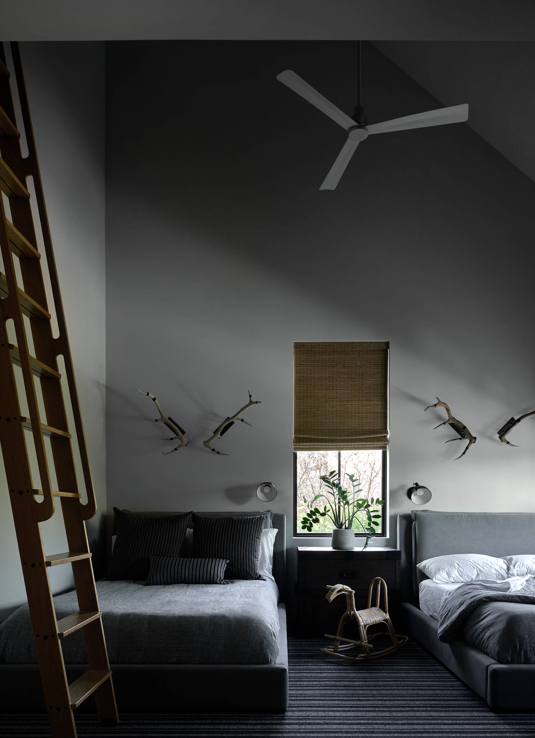 A modern bedroom with two beds and different tones of grey.