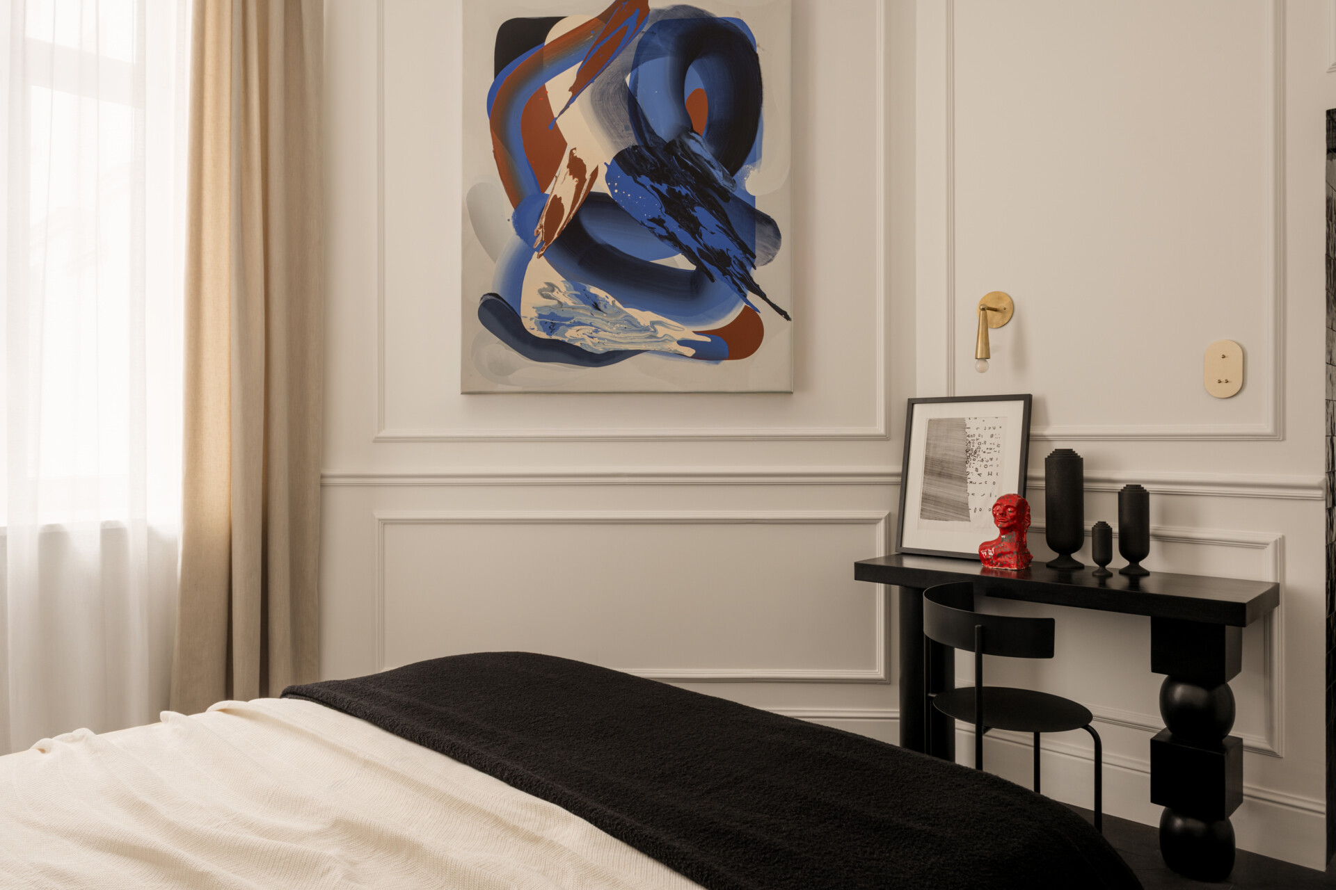 The bed appears to hover, supported by a hidden central leg. Wrapped in Dedar Milano fabric and accented by brass sconces, the bedroom feels serene and weightless. Artworks, sculptures, and handcrafted objects give it soul and quiet personality.