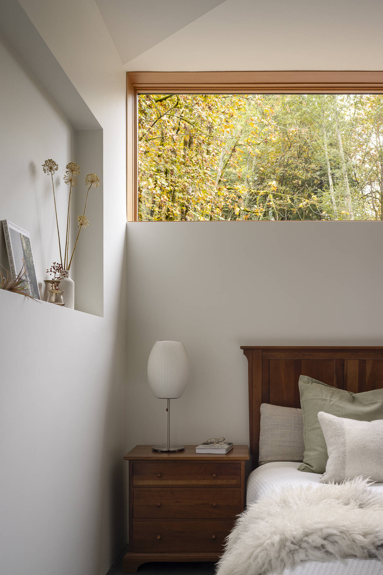 A modern bedroom with a horizontal window and shelving niche.