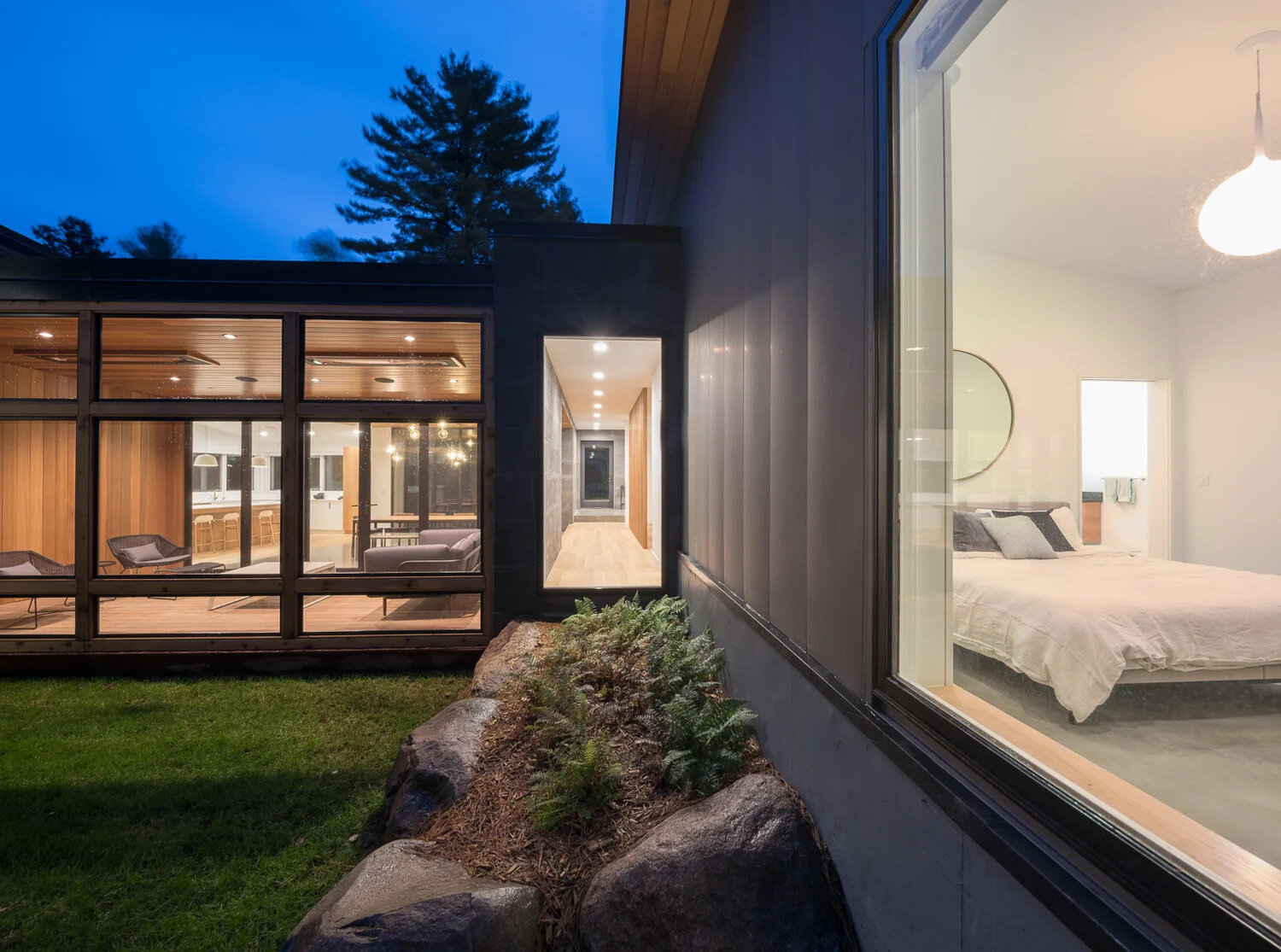 In the bedroom, windows wrap around one end of the room, creating a natural frame for the surrounding forest.