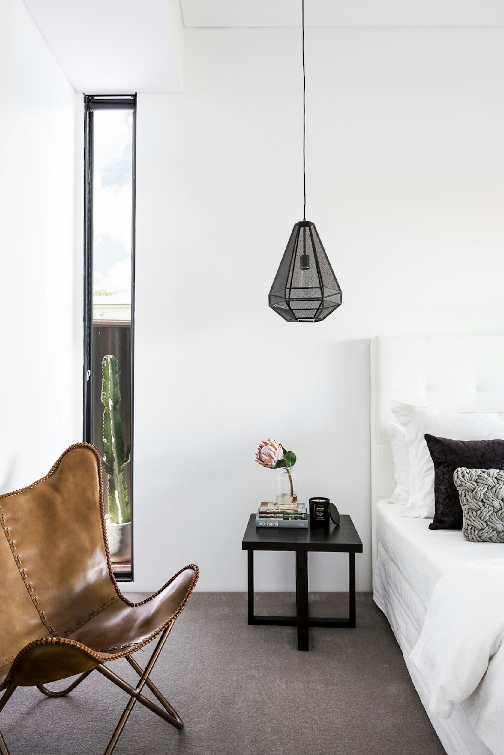 The primary bedroom, tucked away at the rear of this renovated home, follows a soothing palette of white and grey with black accents.