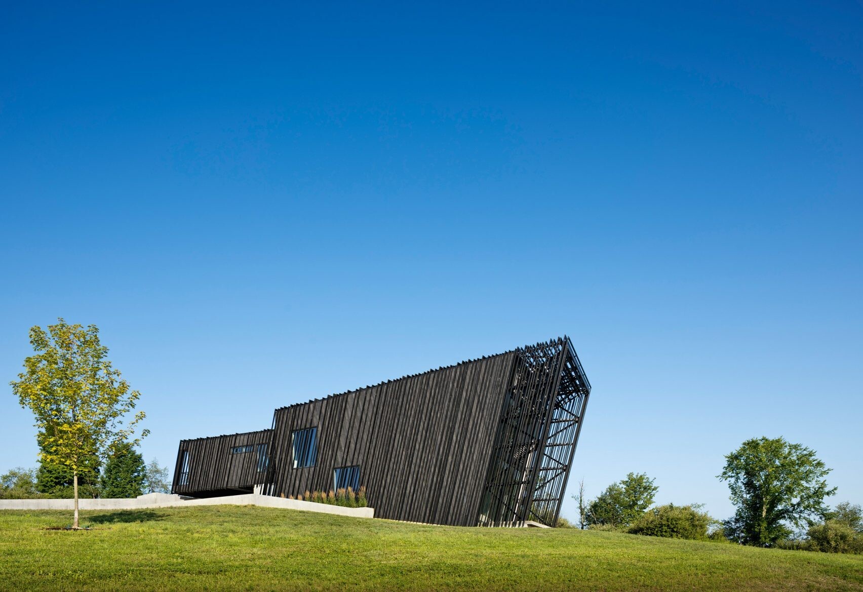 Wrapped in charred timber and set on a concrete base, this sculptural hillside home stands as a minimalist landmark in New York’s Hudson Valley.