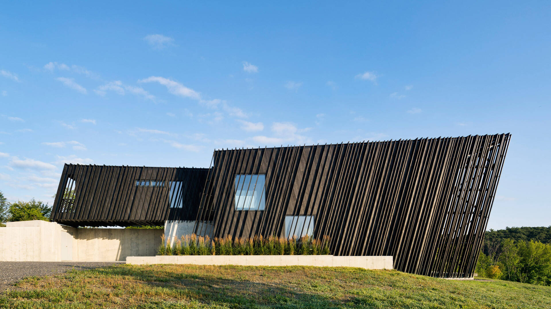 Wrapped in charred timber and set on a concrete base, this sculptural hillside home stands as a minimalist landmark in New York’s Hudson Valley.
