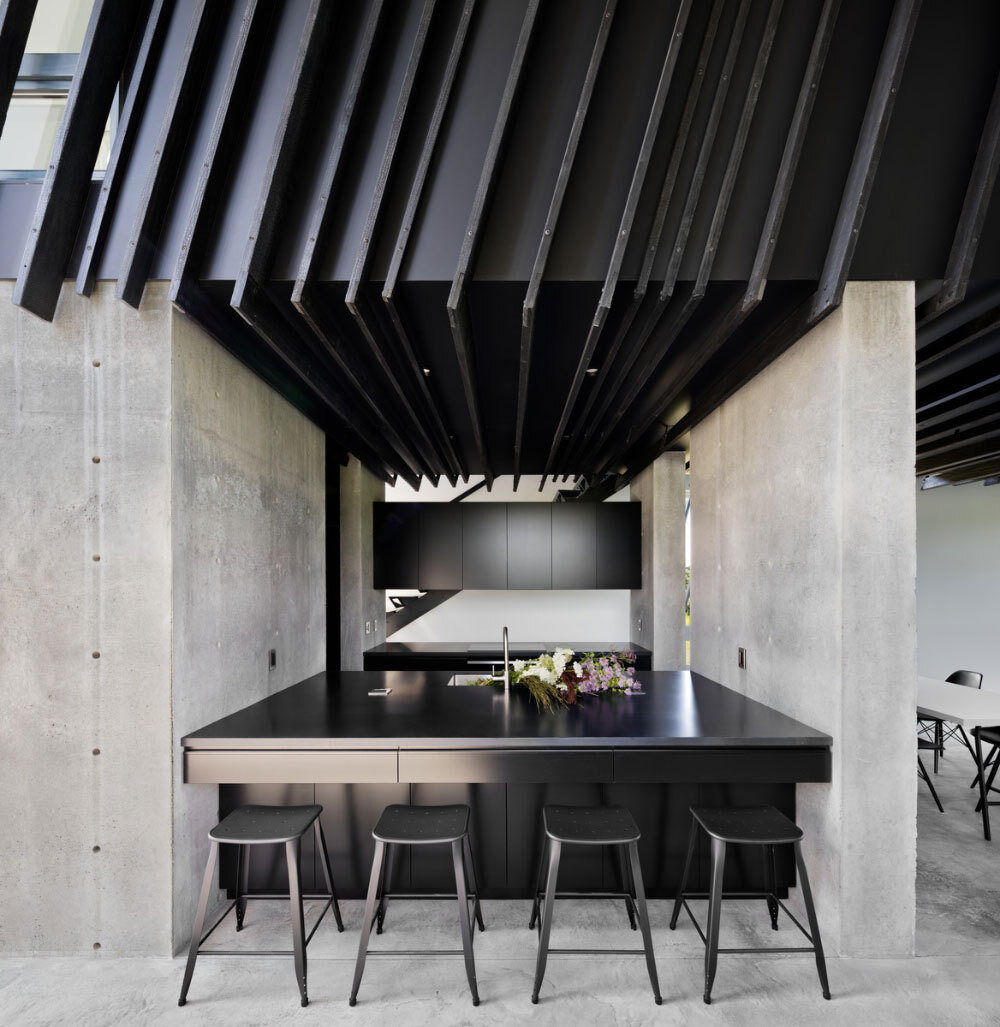 Matte-black cabinetry and a crisp black-and-white dining space define this modern kitchen, sleek, simple, and quietly luxurious.
