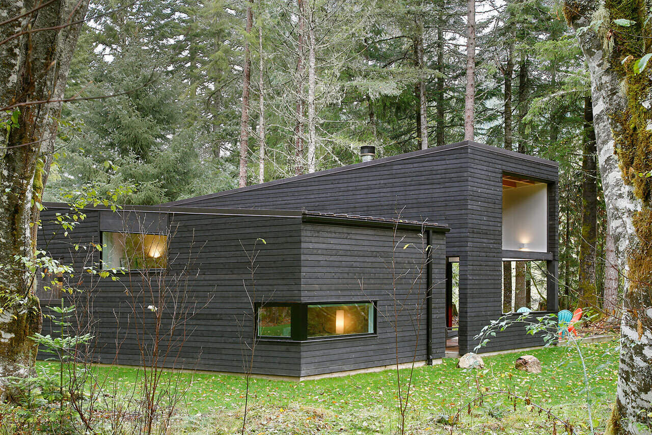 A sleek, single-story house by Robert Hutchison Architecture, wrapped in blackened cedar and nestled quietly among the evergreens near Mount Rainier.