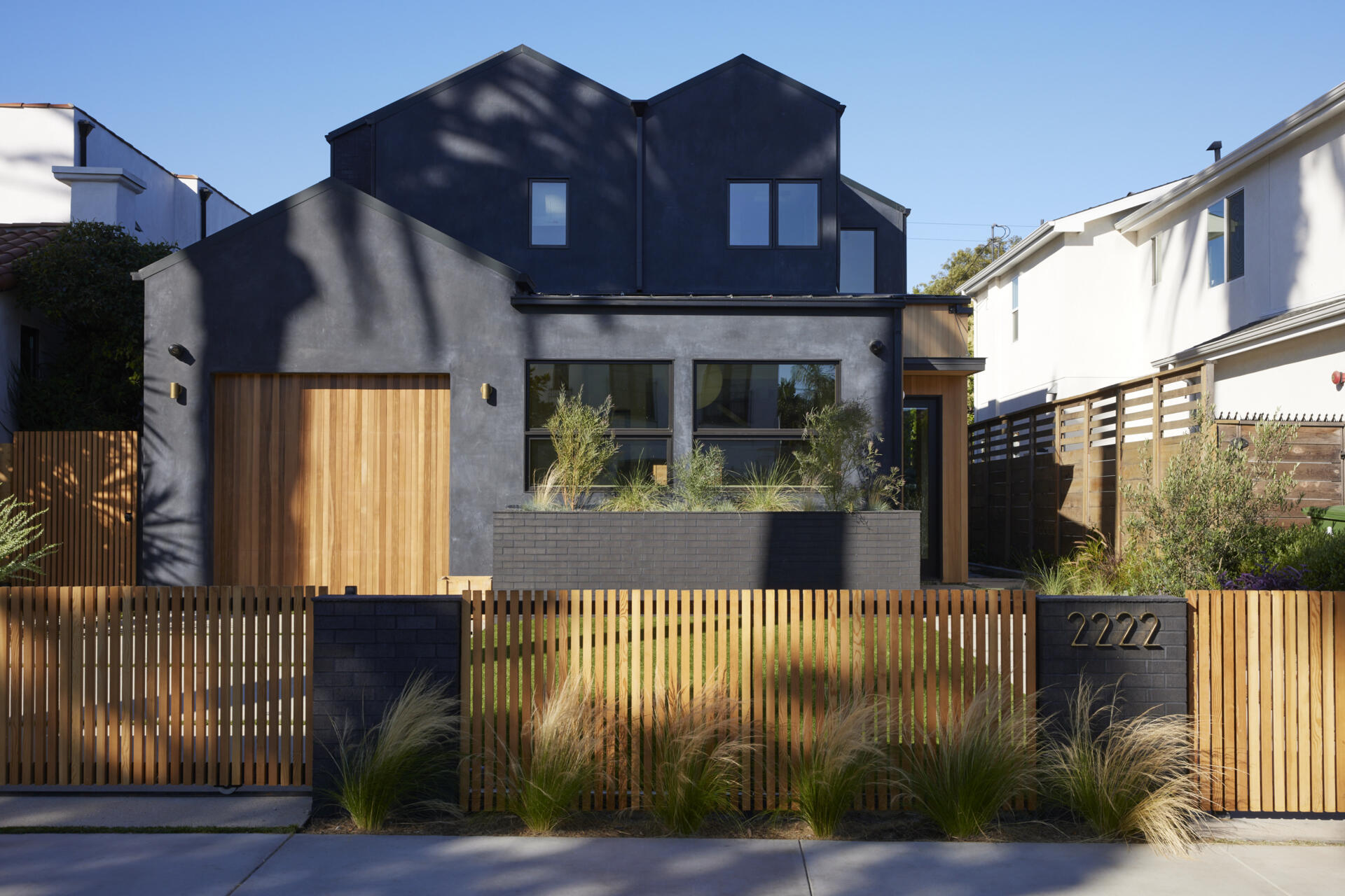 A bold black stucco exterior with warm wood accents creates instant curb appeal, giving this modern family home a striking yet inviting facade.
