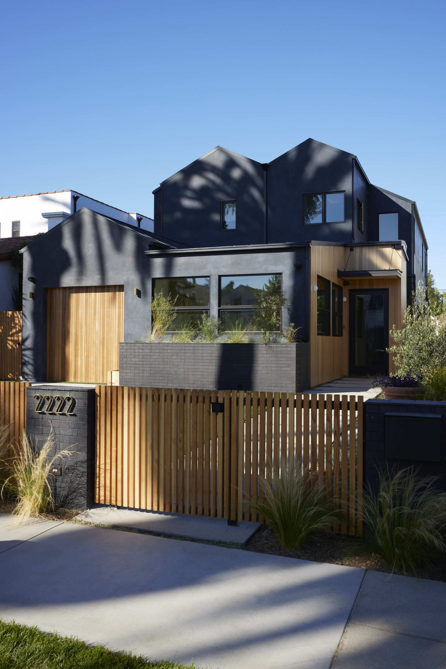 A bold black stucco exterior with warm wood accents creates instant curb appeal, giving this modern family home a striking yet inviting facade.