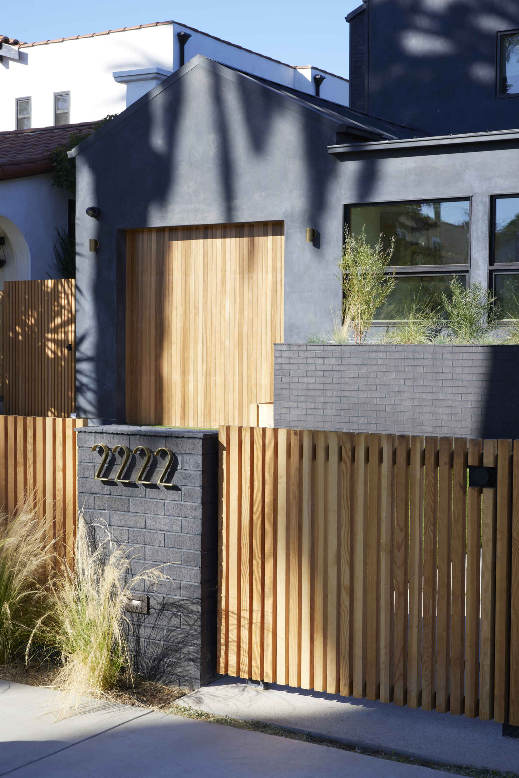 A bold black stucco exterior with warm wood accents creates instant curb appeal, giving this modern family home a striking yet inviting facade.