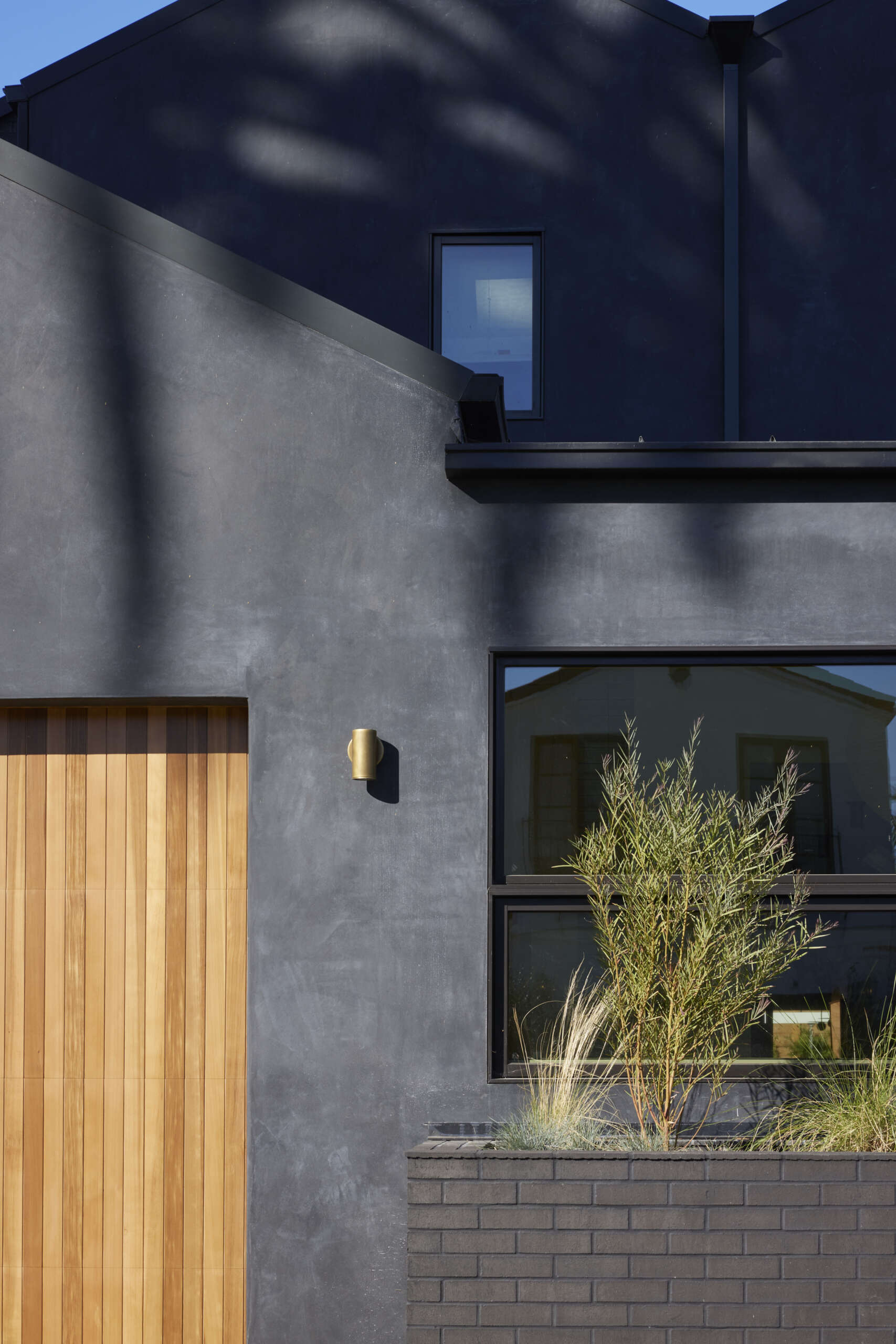 A bold black stucco exterior with warm wood accents creates instant curb appeal, giving this modern family home a striking yet inviting facade.