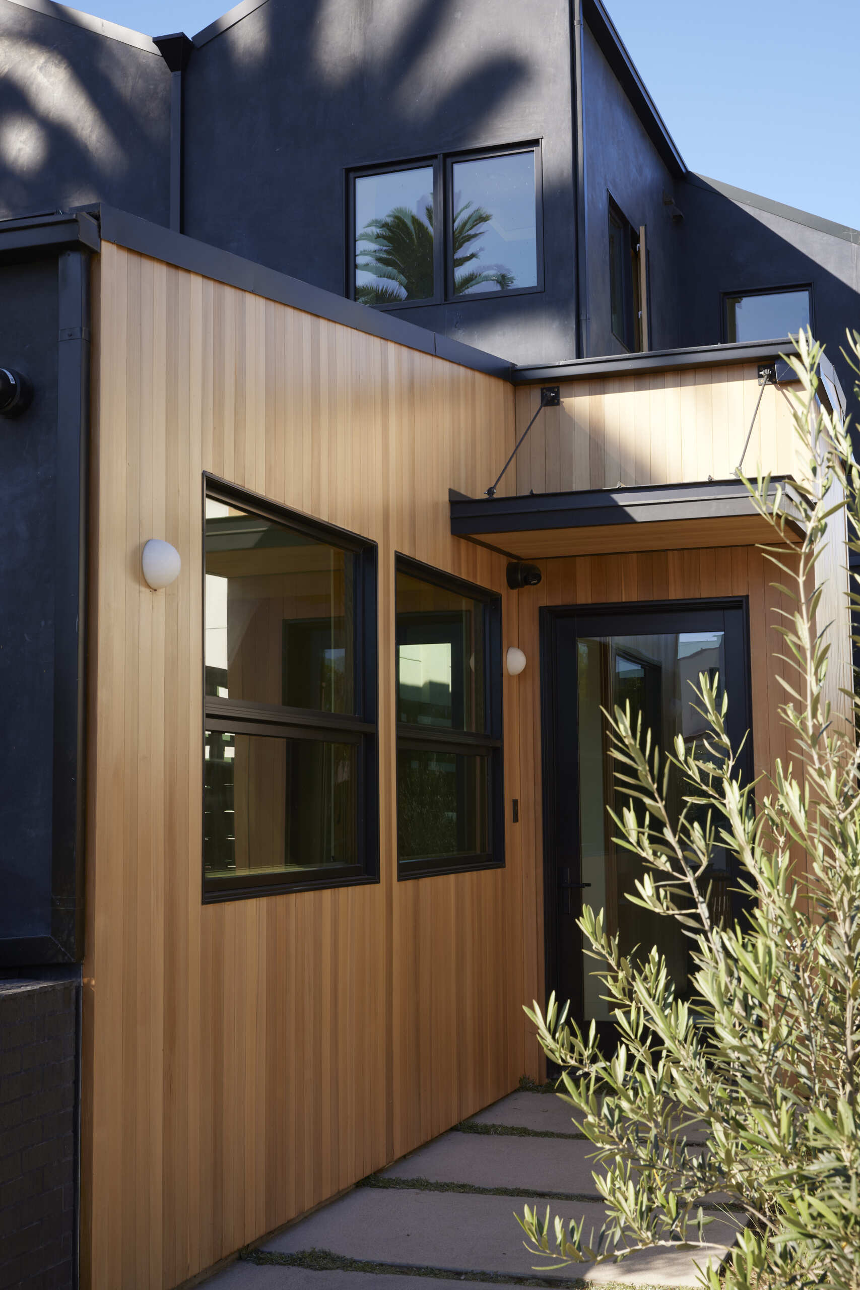 The wood-clad entry frames a welcoming threshold, blending warmth with clean lines to set the stage for the home’s layered design.