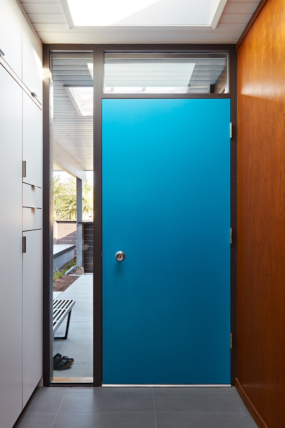 A bright blue Eichler front door welcomes guests with vintage charm and modern flair in this San Mateo renovation.
