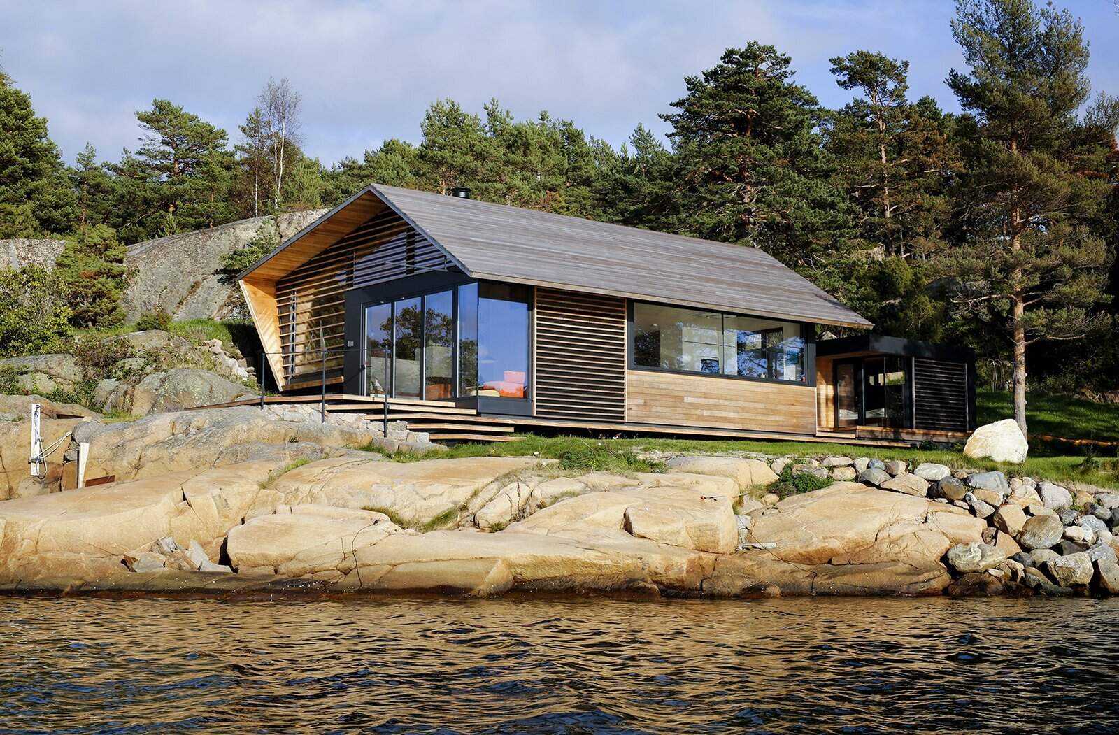 A modern cedar-clad cabin by the water seamlessly blends architecture and landscape.