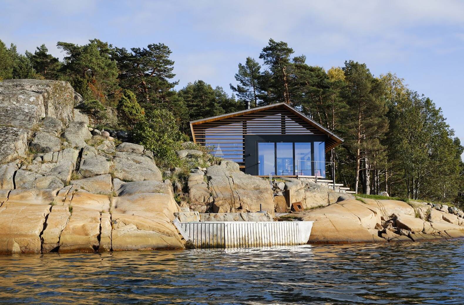 A modern cedar-clad cabin by the water seamlessly blends architecture and landscape.