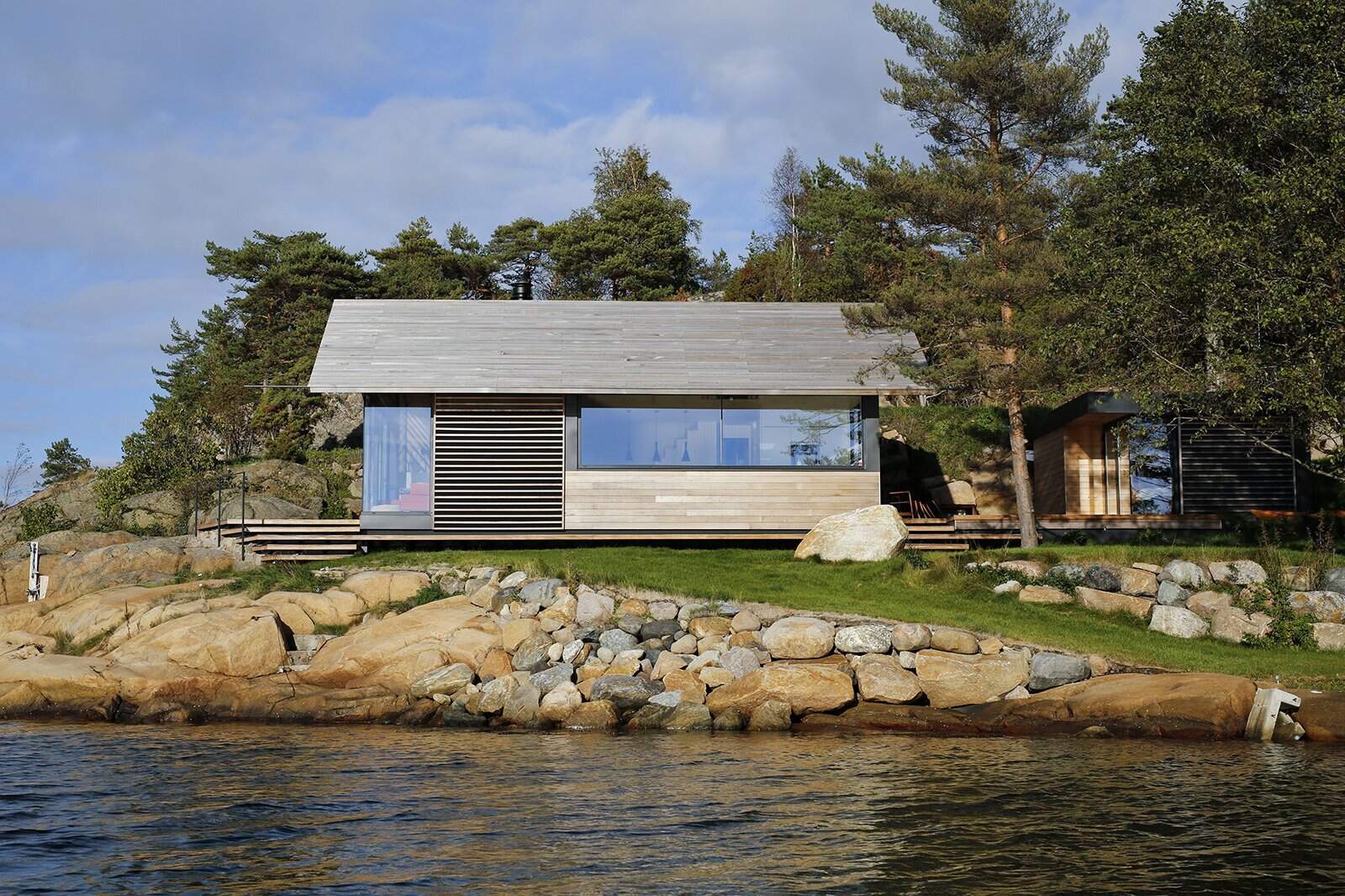 A modern cedar-clad cabin by the water seamlessly blends architecture and landscape.