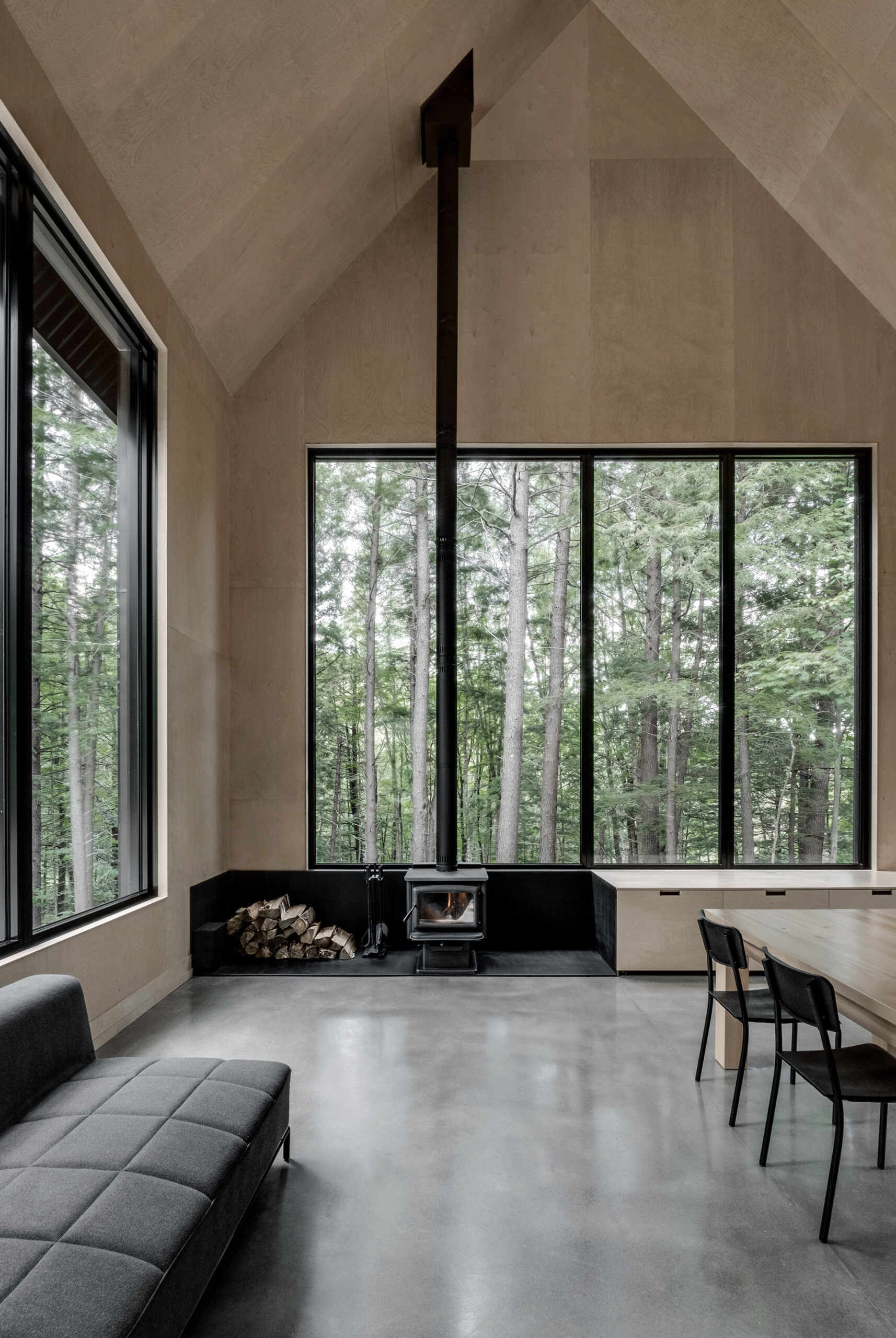 Warm wood tones, a sleek fireplace, and high vaulted ceilings make this open living space the heart of the modern forest cottage.