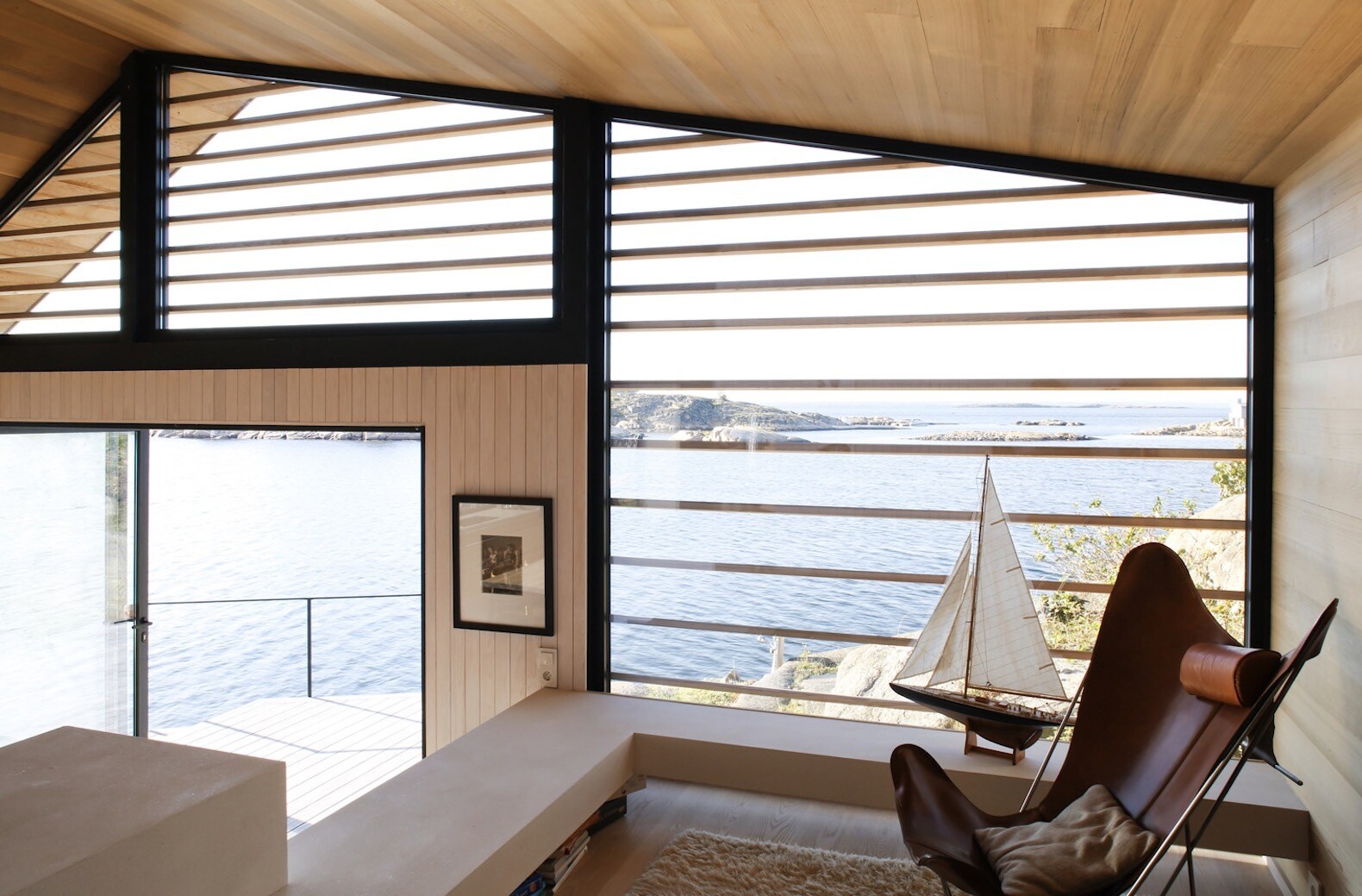 In this small cabin, the living room and kitchen share the main level, with the living space flowing directly onto a timber deck that overlooks the sea.