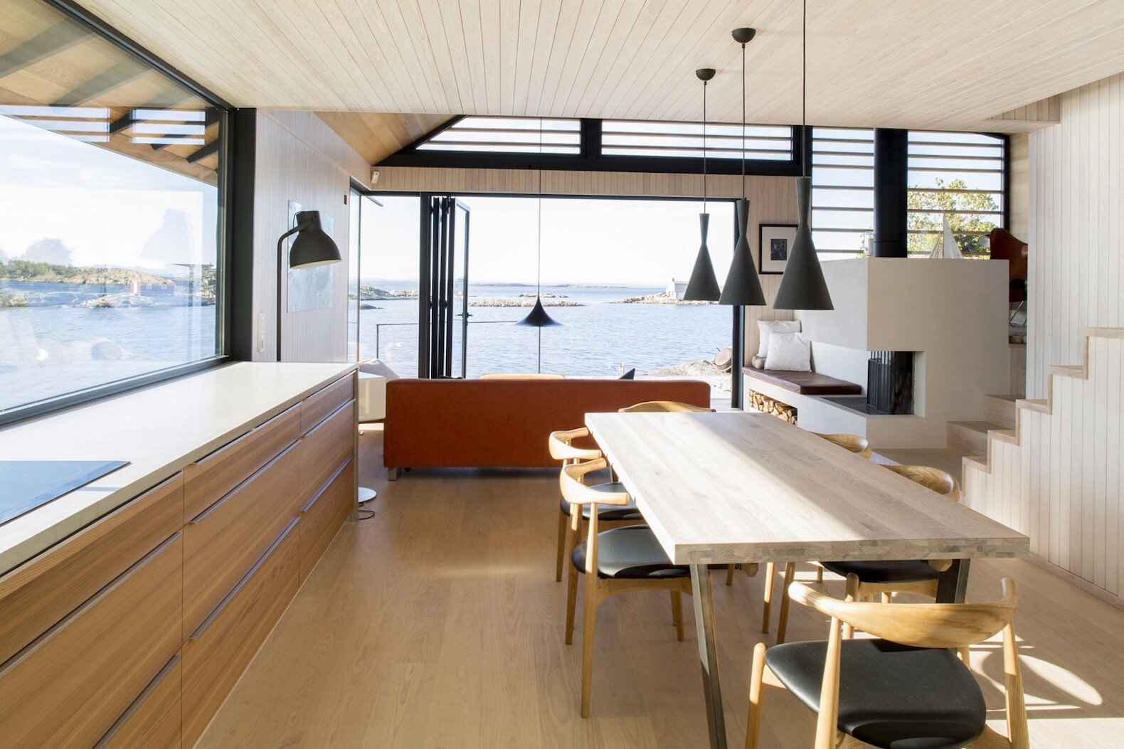 In this small cabin, the living room and kitchen share the main level, with the living space flowing directly onto a timber deck that overlooks the sea.
