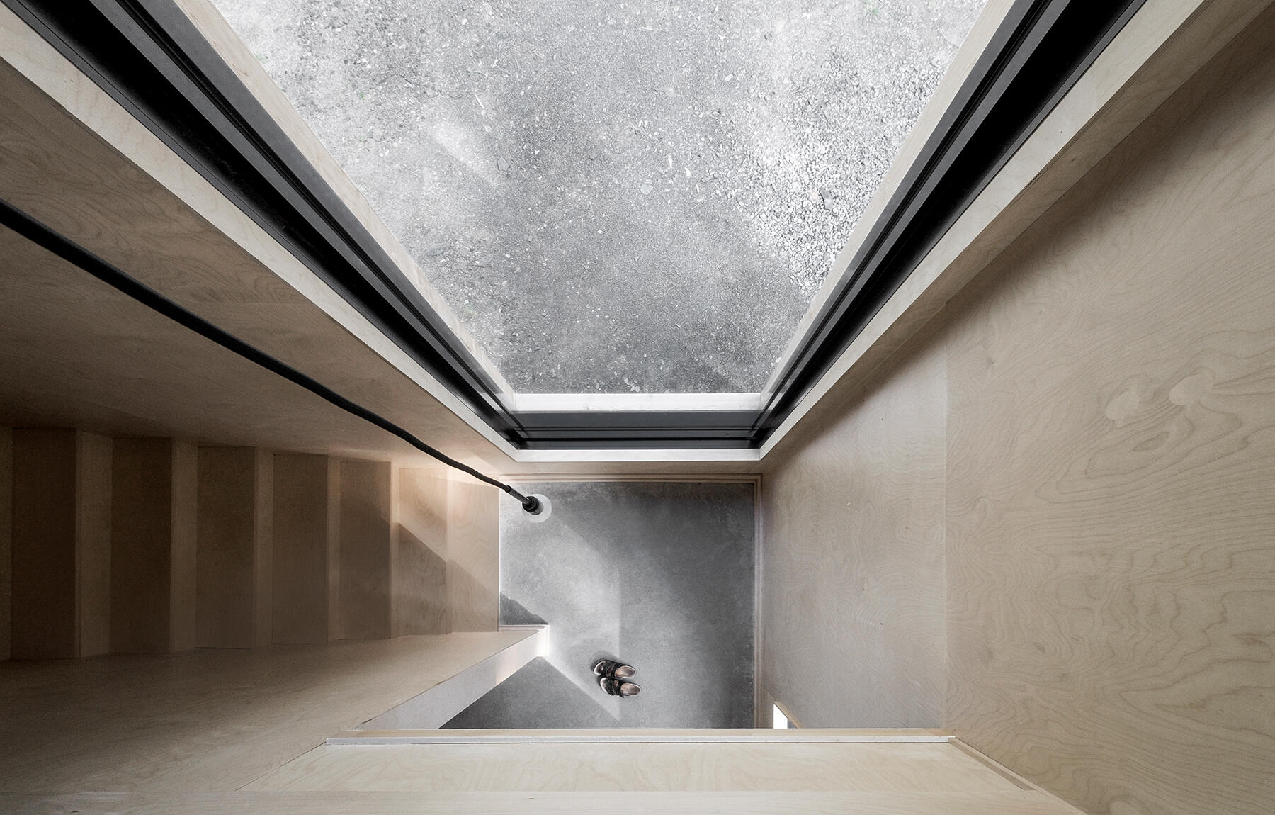 A wooden staircase leads to tranquil bedrooms above, where light and landscape define the calm, airy mood of the cottage.