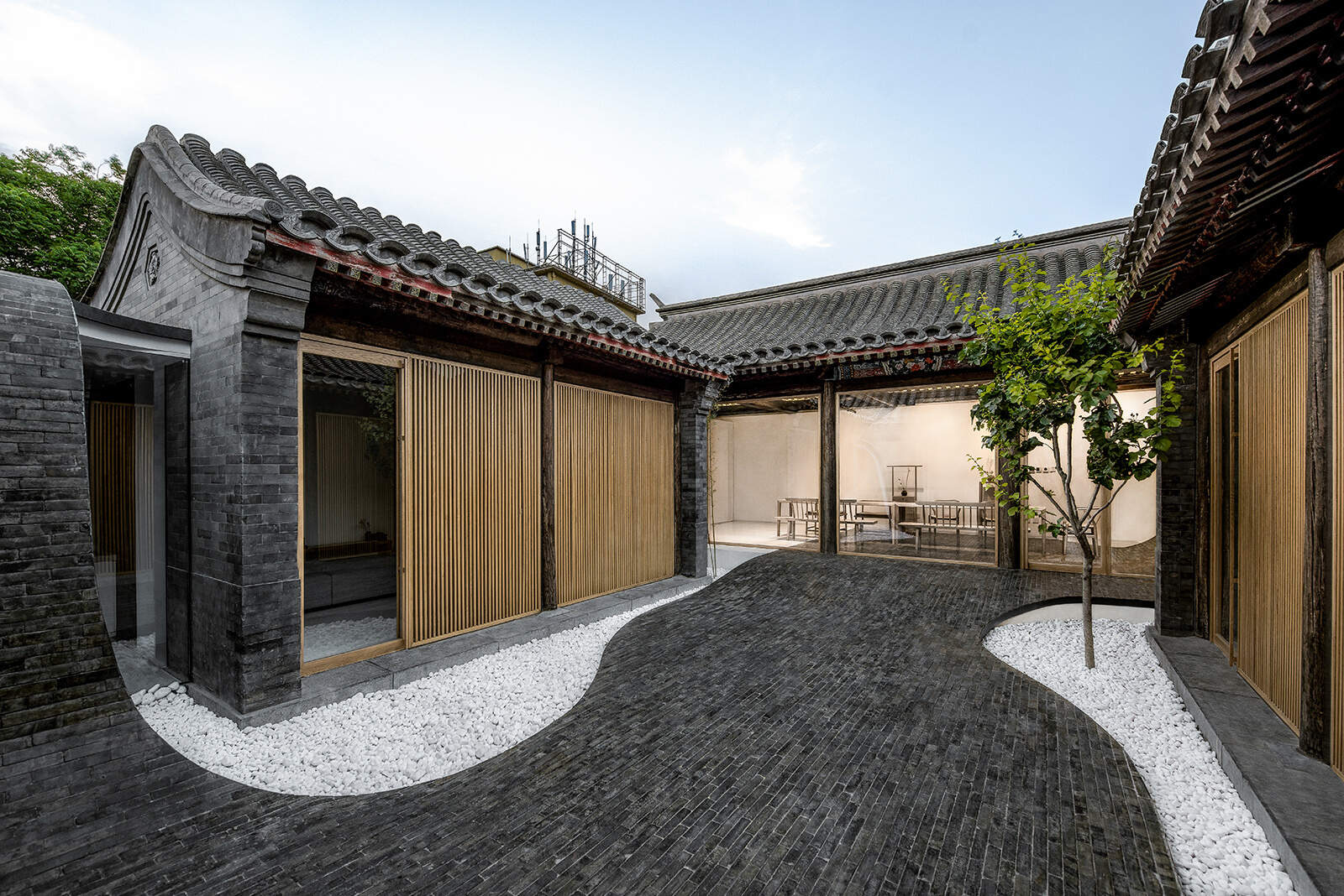 Dark tiles curve from roof to courtyard, connecting indoor and outdoor spaces and creating a dynamic walking path that comes alive at night.