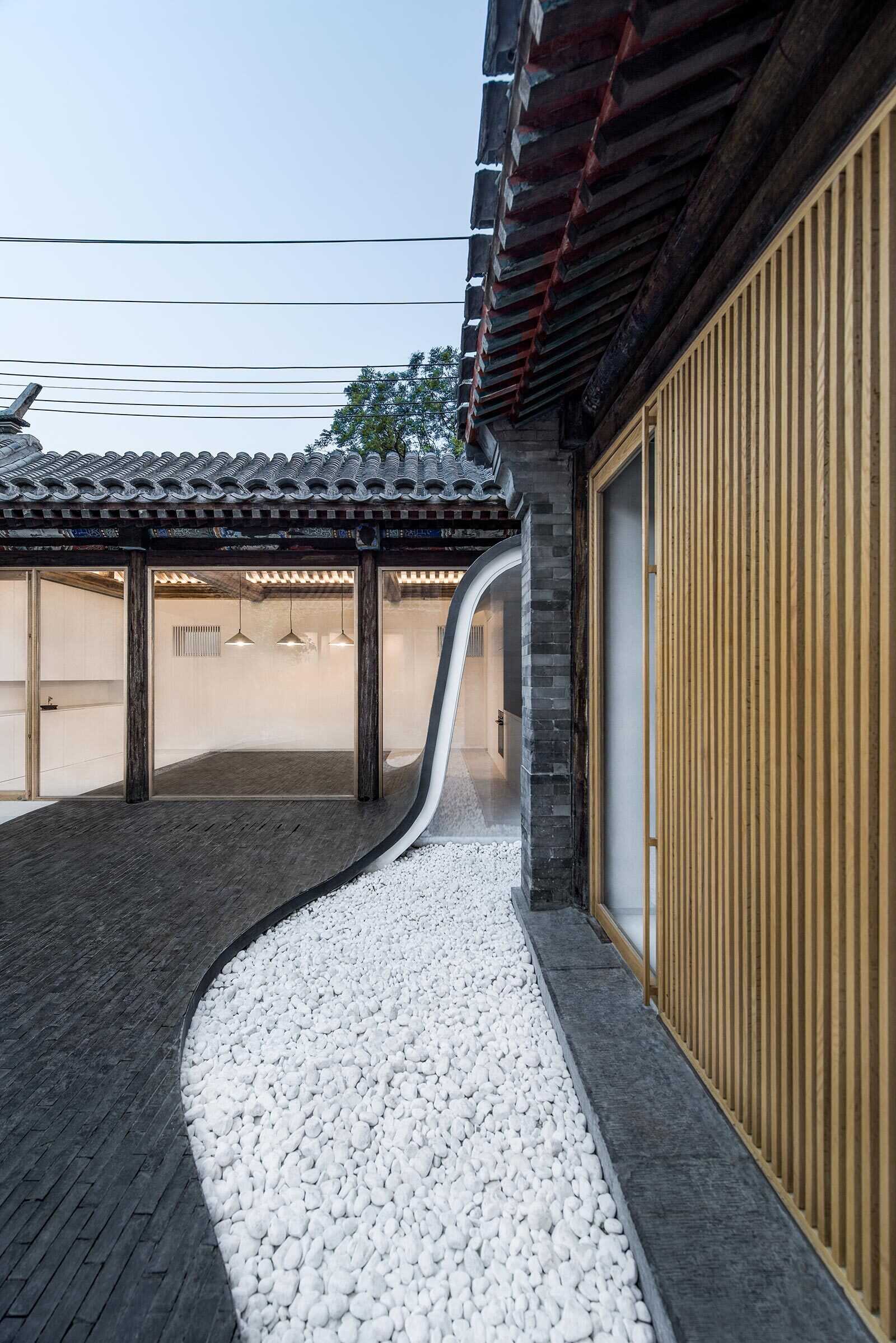 Dark tiles curve from roof to courtyard, connecting indoor and outdoor spaces and creating a dynamic walking path that comes alive at night.