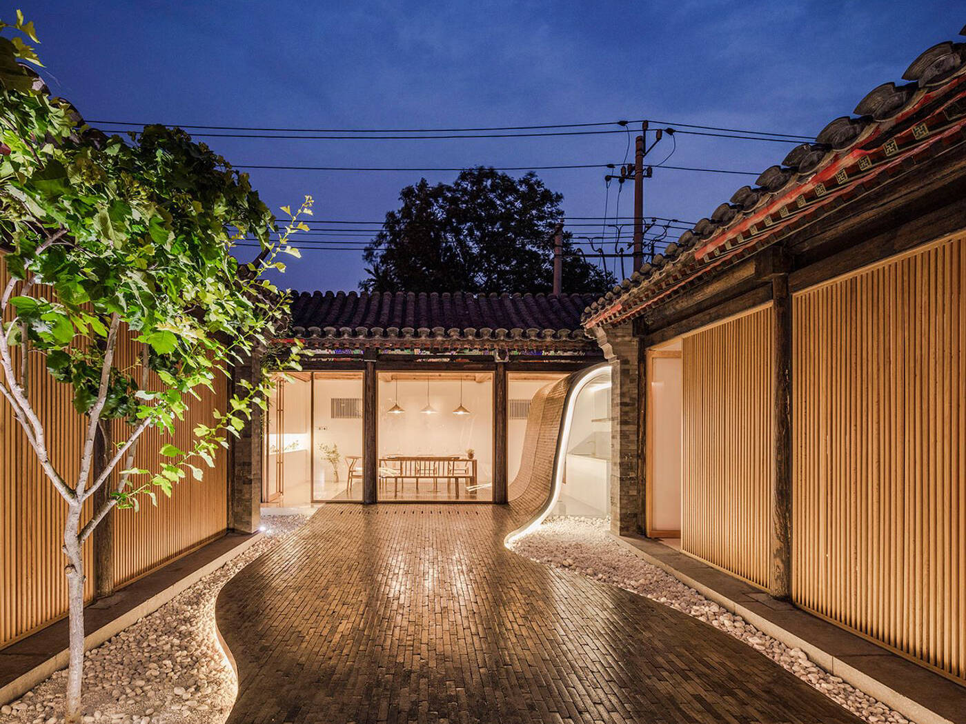 The Twisting Courtyard in Beijing invites visitors through a red door into a historic Siheyuan, now transformed into a modern, flexible public space.