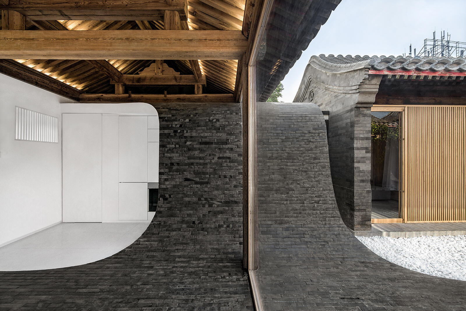 Dark tiles curve from roof to courtyard, connecting indoor and outdoor spaces and creating a dynamic walking path that comes alive at night.