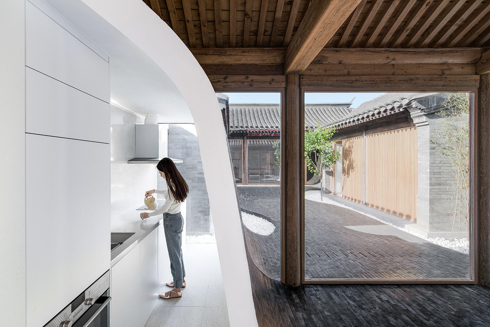 Inside, a small modern kitchen hides behind curved tile walls, keeping functionality discreet while enhancing the fluid design.