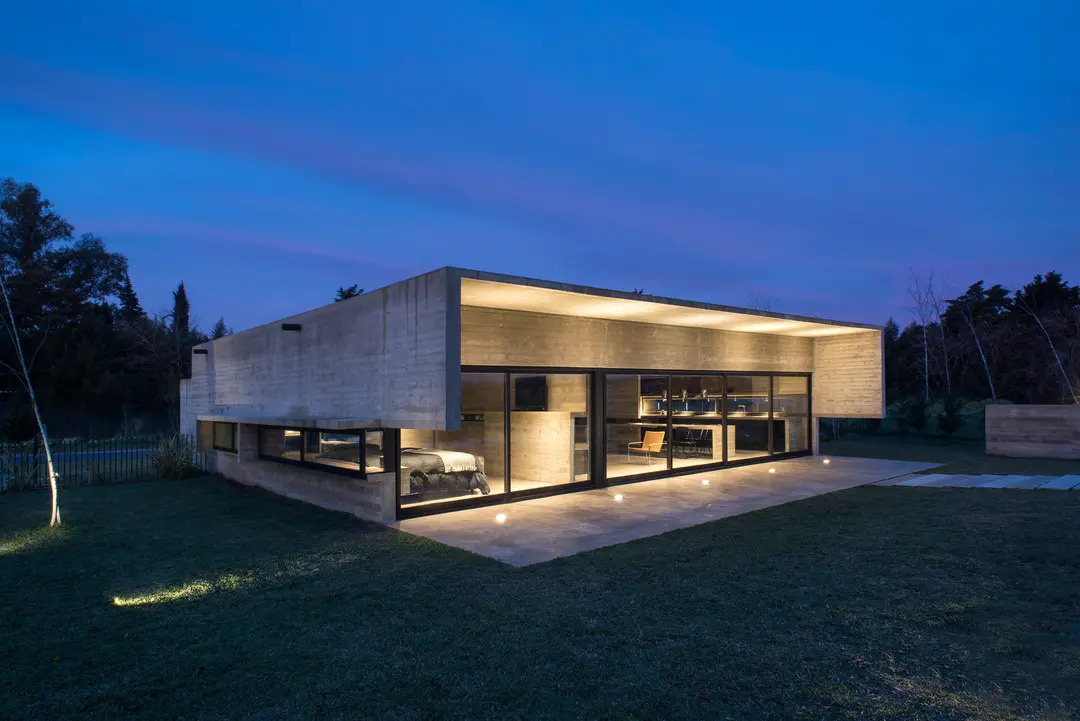 A modern concrete home in Buenos Aires with pools at both ends and a glowing overhang that transforms at night.
