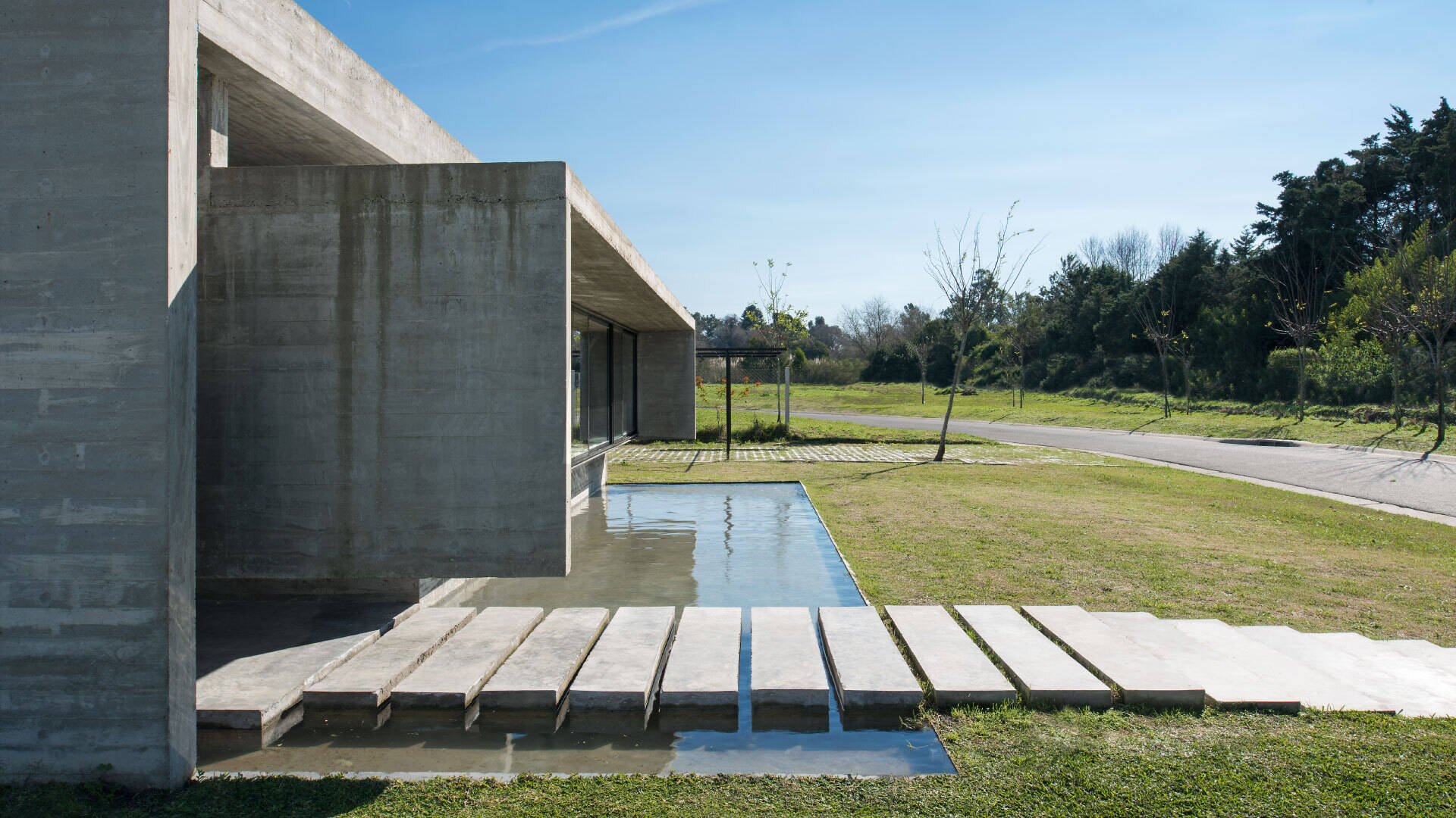 A modern concrete home in Buenos Aires with pools at both ends and a glowing overhang that transforms at night.