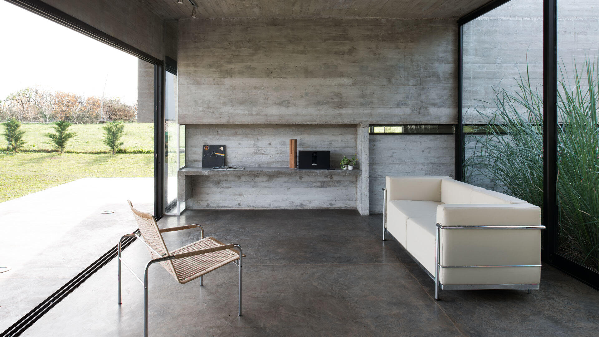 An airy concrete living room with sliding glass doors that open fully to the garden.