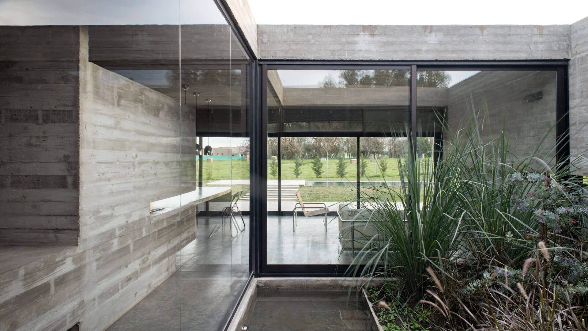 A serene courtyard at the heart of a concrete home, where sunlight and reflections create calm throughout the day.