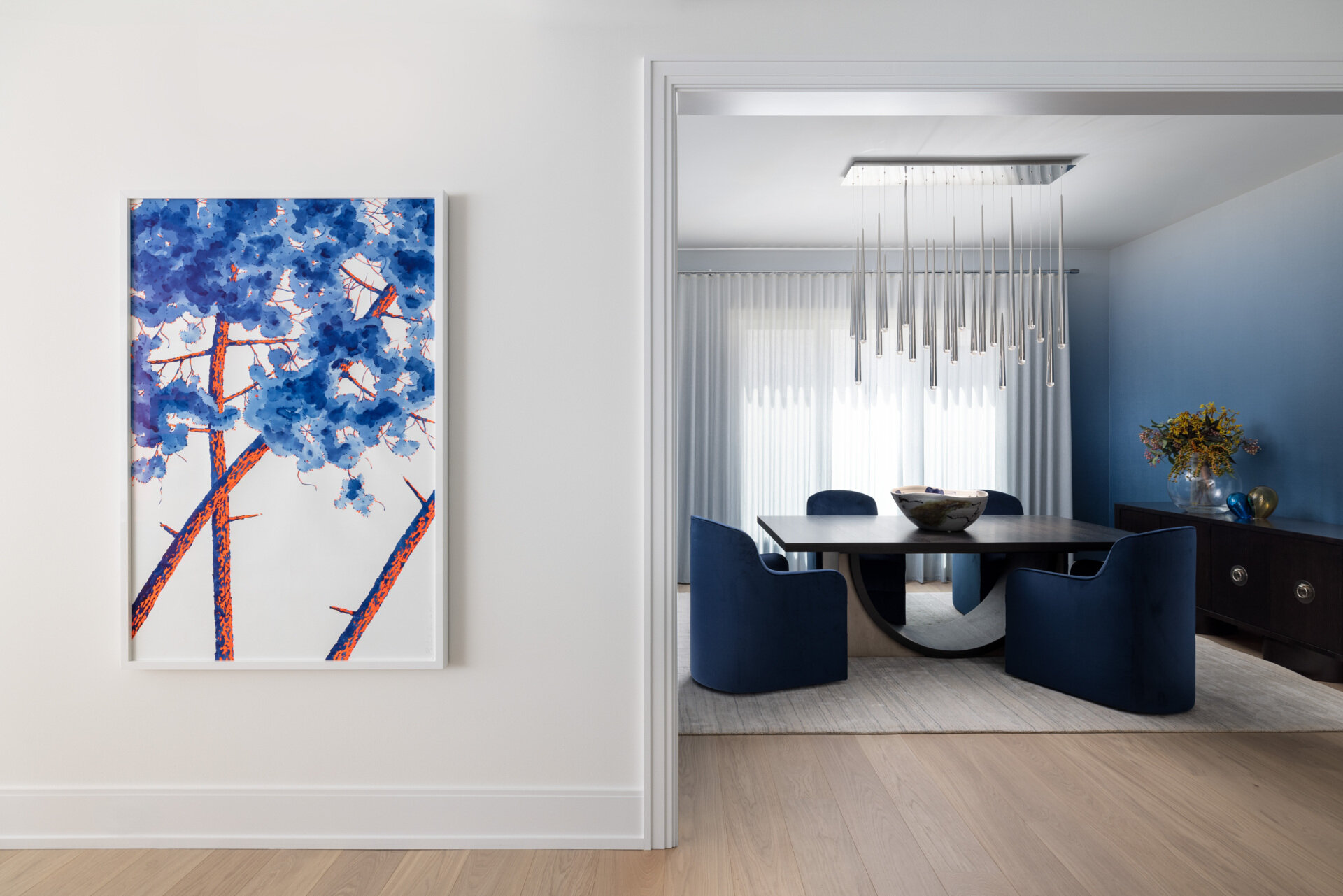 The dining room leans into atmosphere. A wood table, comfortable chairs, and a chandelier with a raindrop shimmer create a soft halo after dark. The walls carry gentle color, just enough to warm the scene without shouting. It is the kind of room that makes every dinner look like a celebration.
