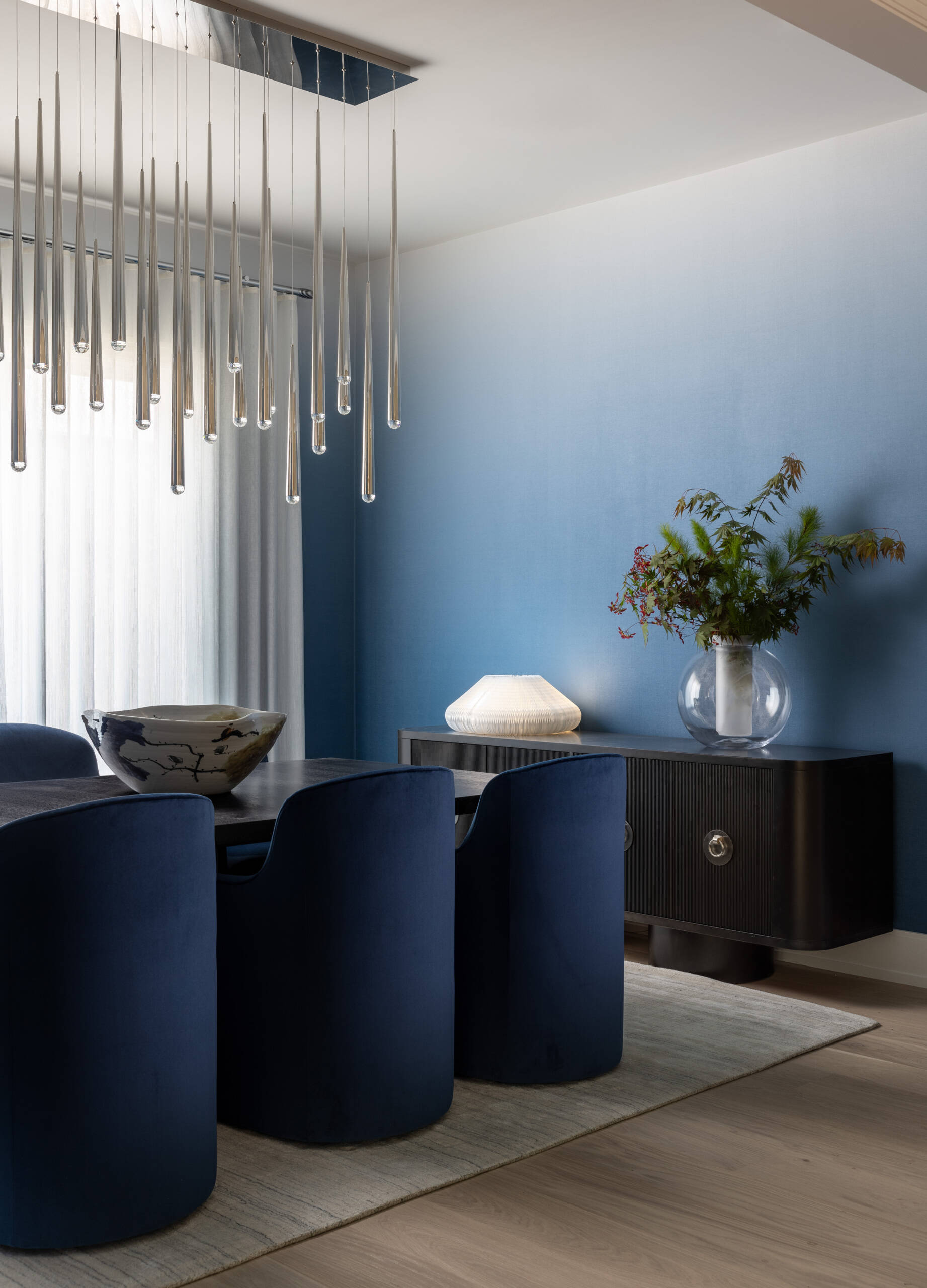 The dining room leans into atmosphere. A wood table, comfortable chairs, and a chandelier with a raindrop shimmer create a soft halo after dark. The walls carry gentle color, just enough to warm the scene without shouting. It is the kind of room that makes every dinner look like a celebration.
